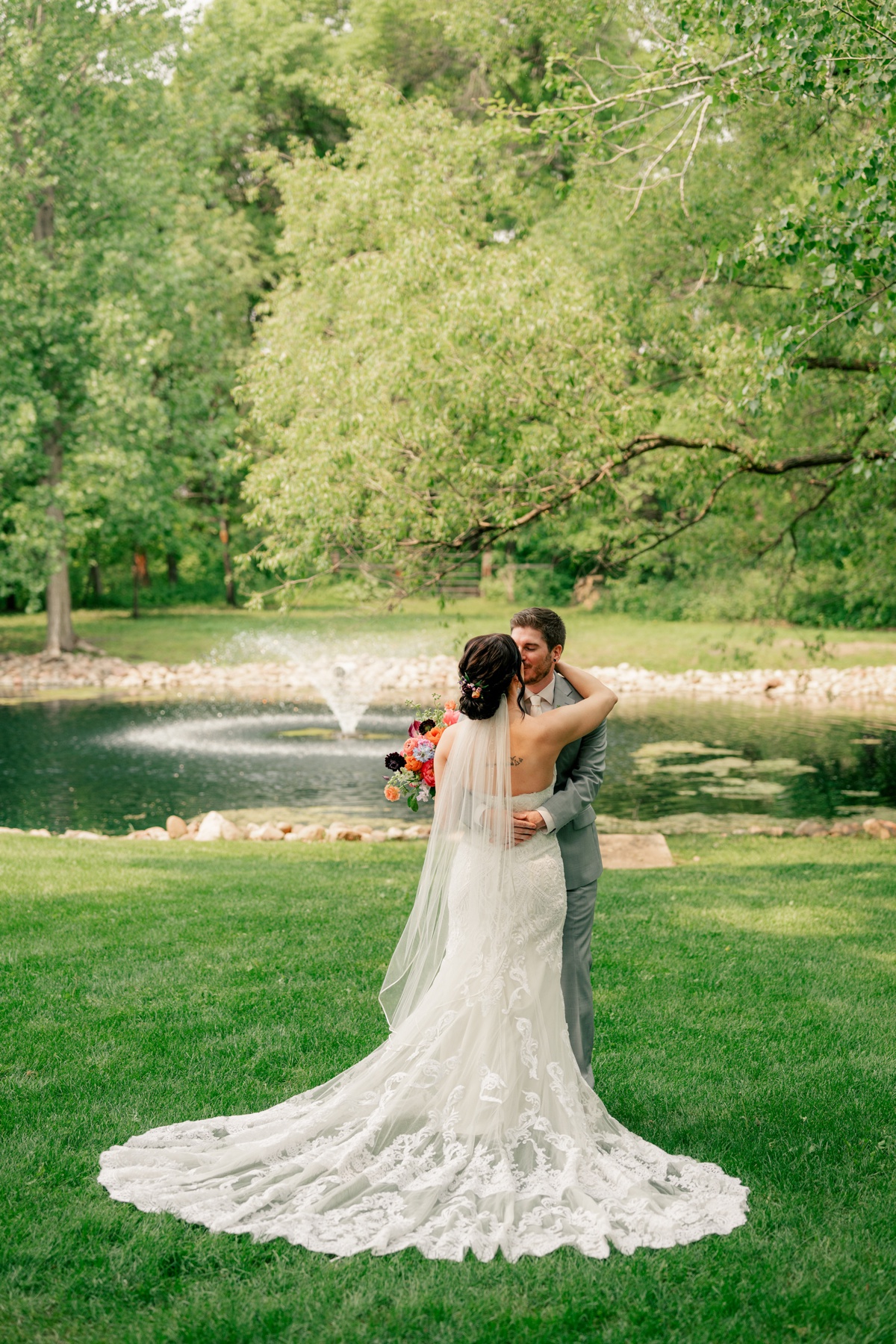 Bride and groom, kissing near fountain for vibrant summer wedding