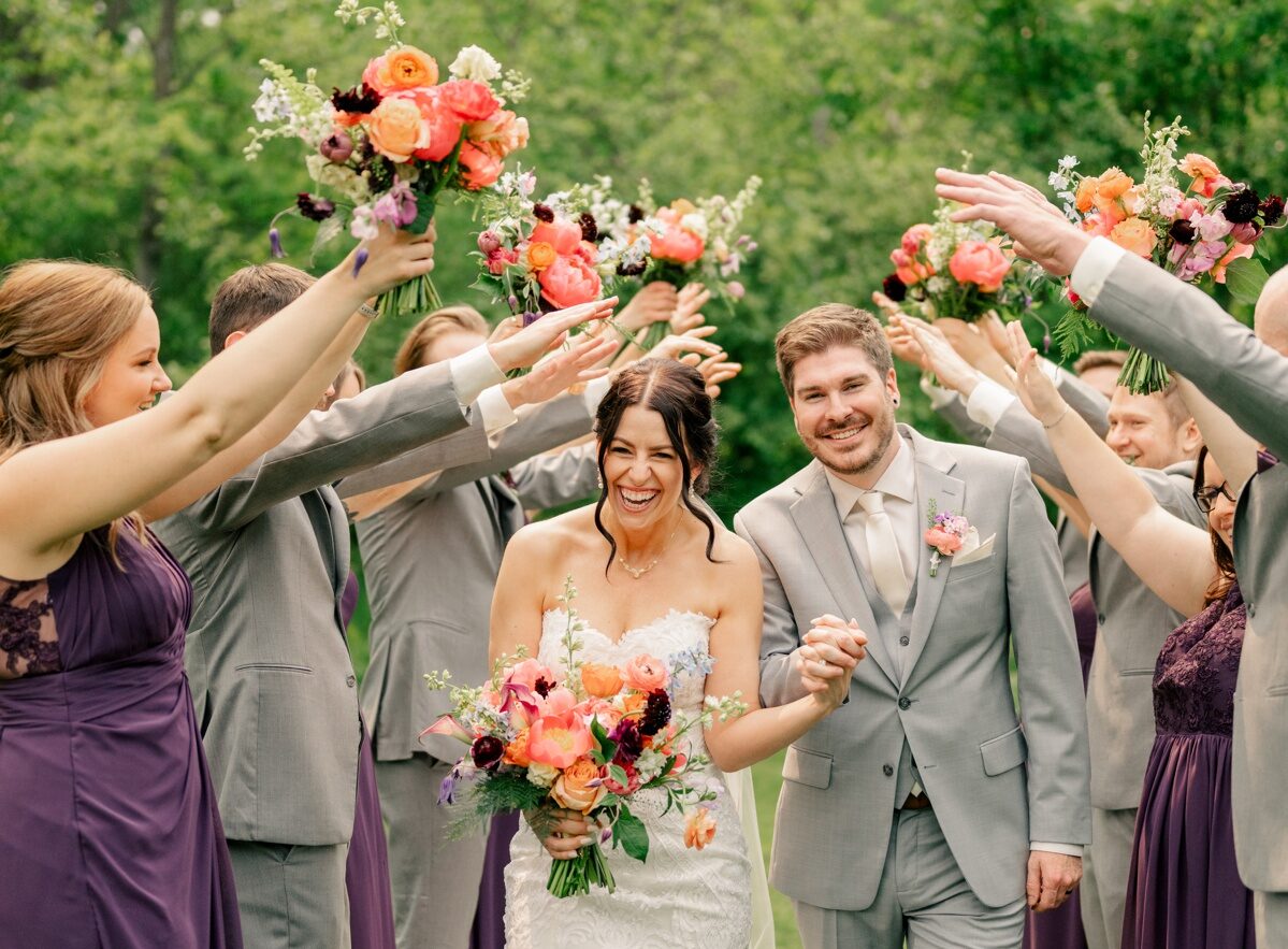 Bride and groom celebrate with wedding party during vibrant summer wedding