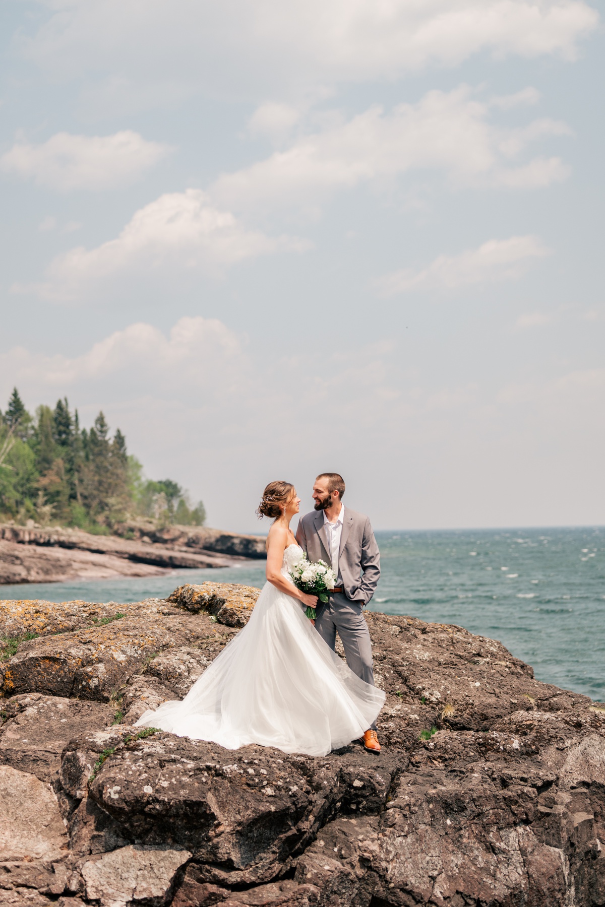 Couple dressed in wedding clothes smile at each other by Rule Creative Co.