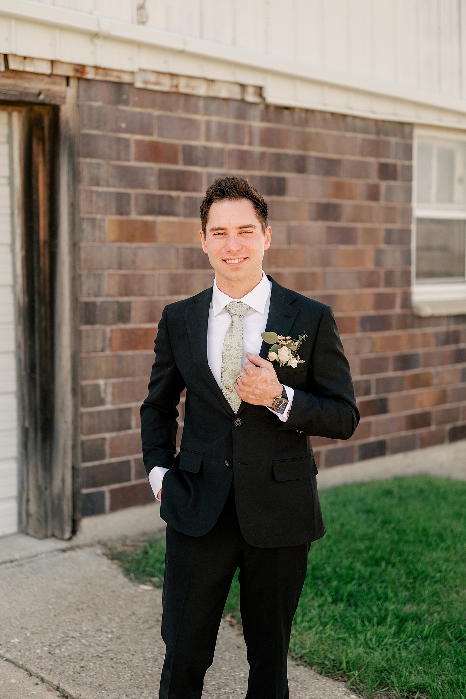 groom with green tie and black suit outside by Rule Creative Co