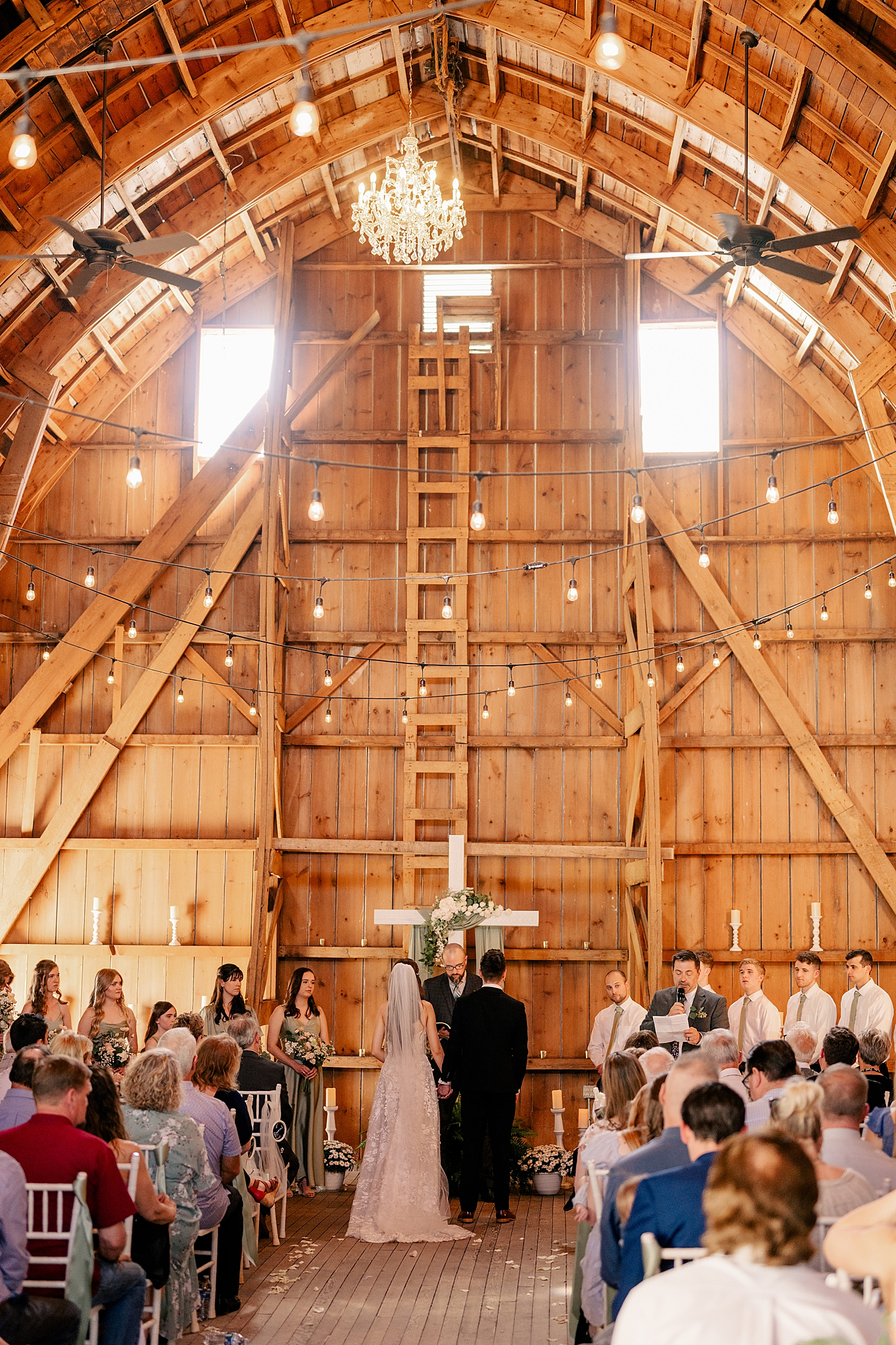 husband and wife stand at alter in large wooden building by Rule Creative Co