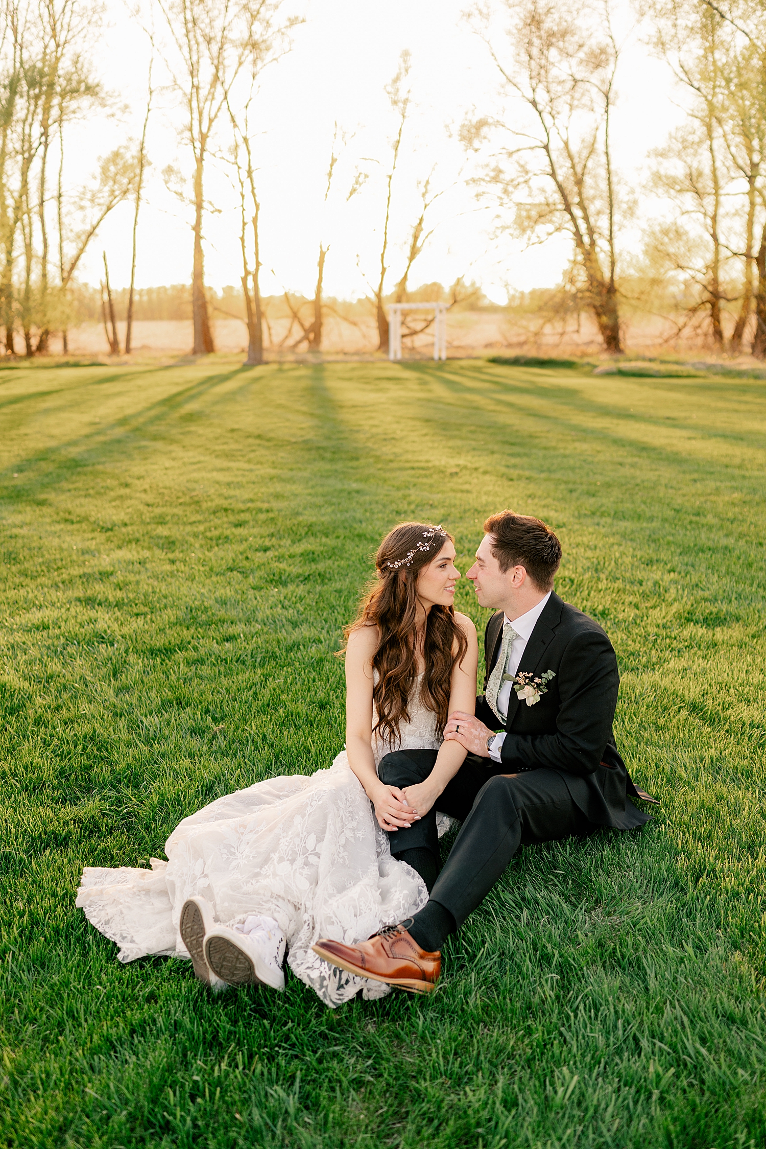 couple sit in the grass together during golden hour by Minnesota wedding photographer