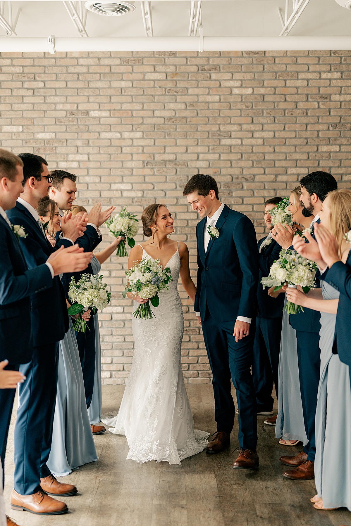 Minnesota Wedding Photographer captures Bride and Groom walking between cheering bridal party.