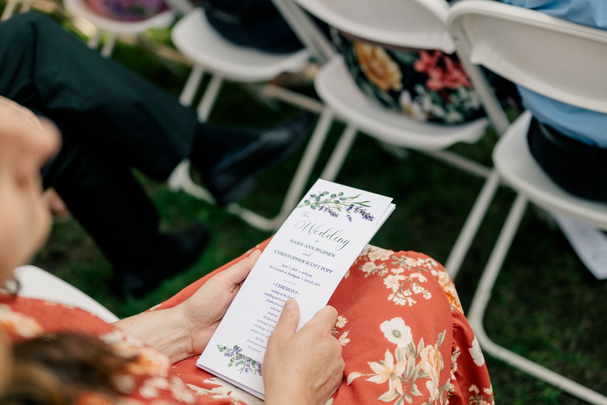 Minnesota Wedding Photographer captures guest holding custom wedding pamphlet 