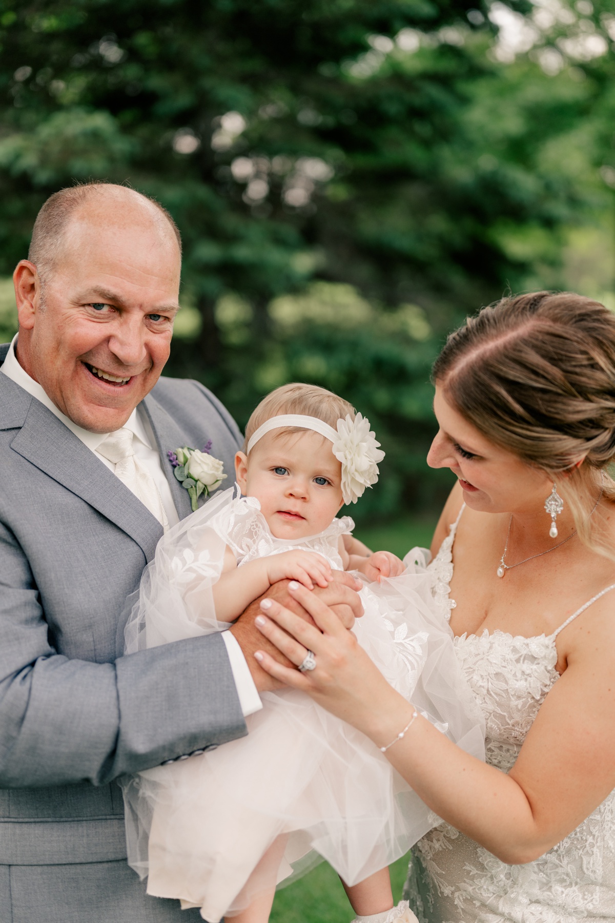 Minnesota Wedding Photographer captures bride and groom posing with their baby daughter