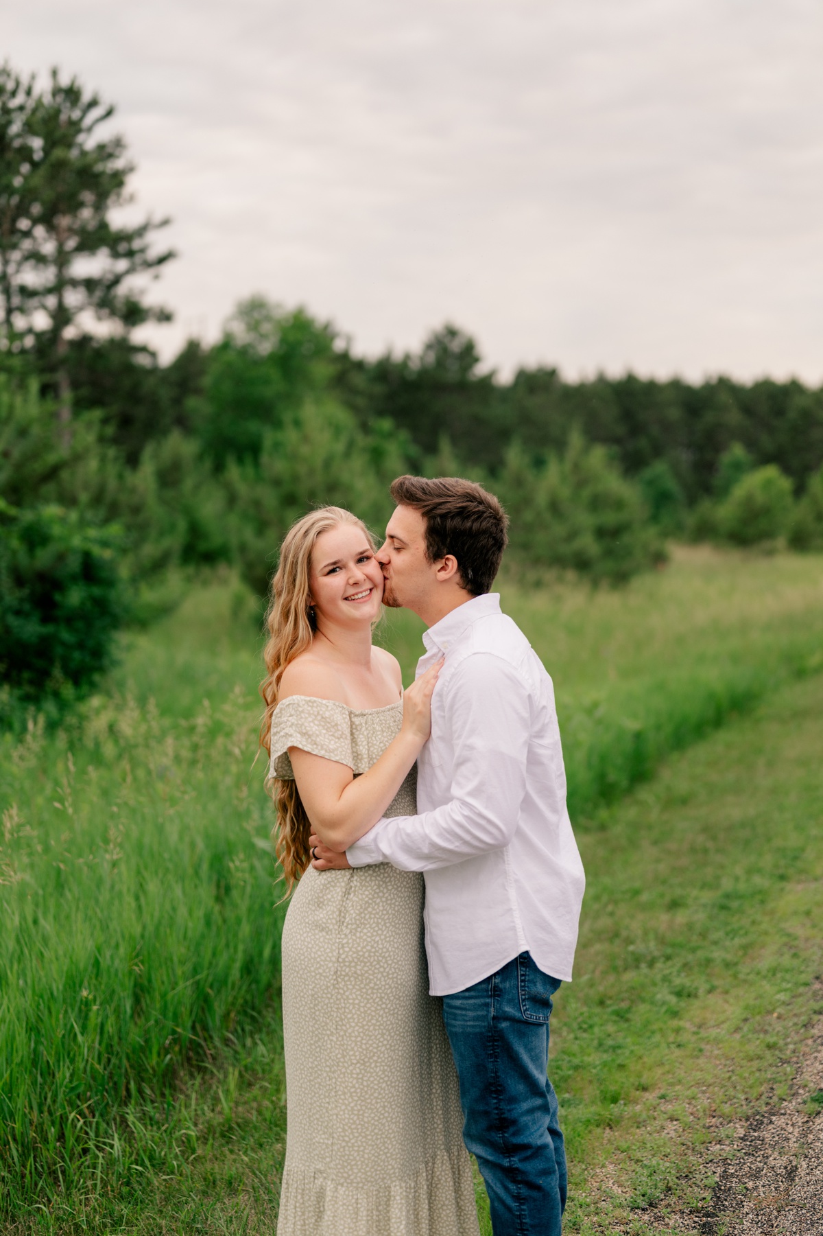 Young man kissing his fiance's cheek by Rule Creative Co