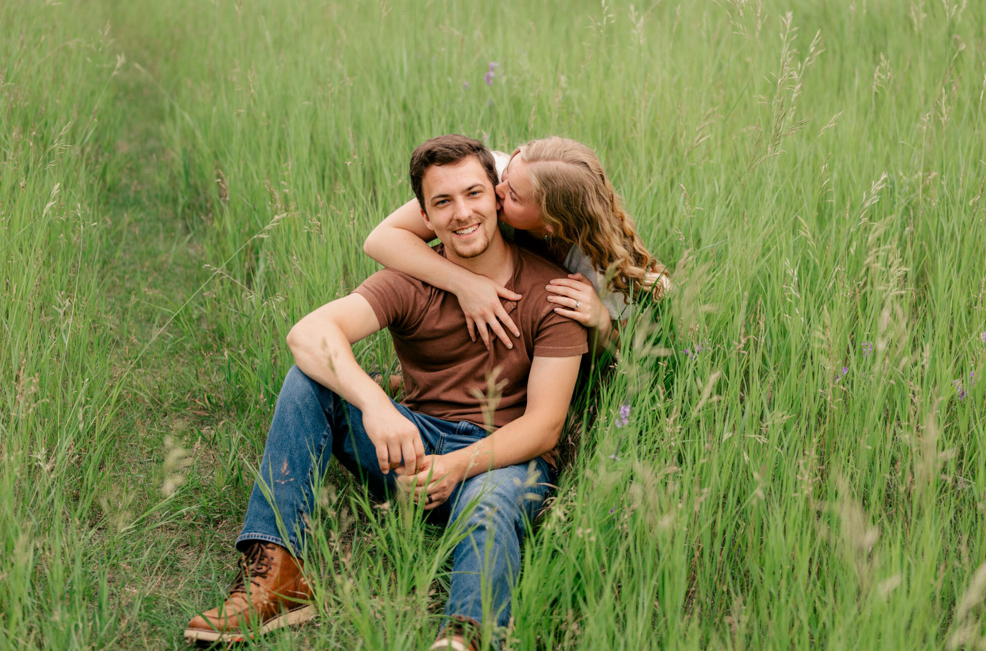 Young couple snuggle in a field by Rule Creative Co