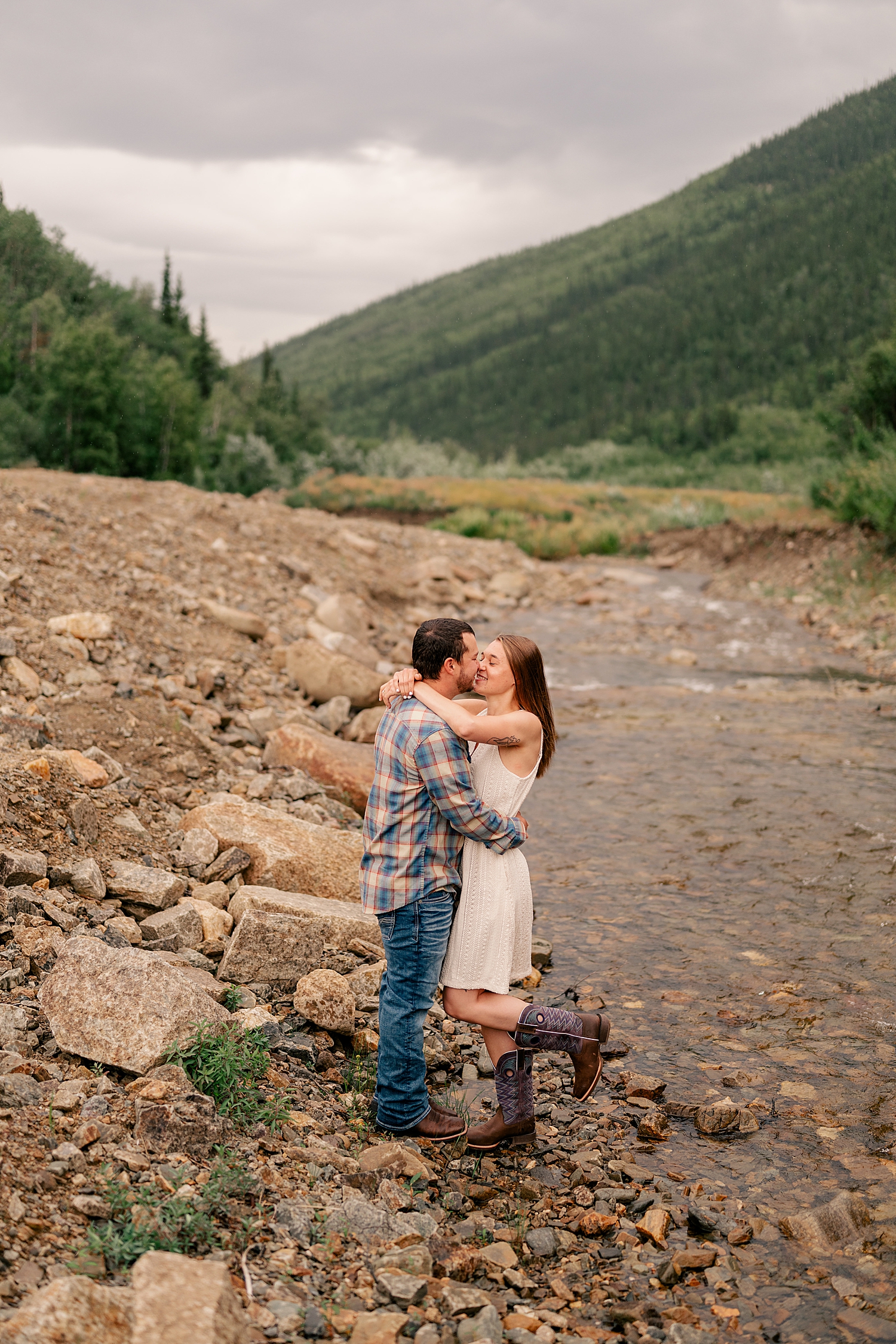 woman in white dress kisses man in creek by Minnesota wedding photographer