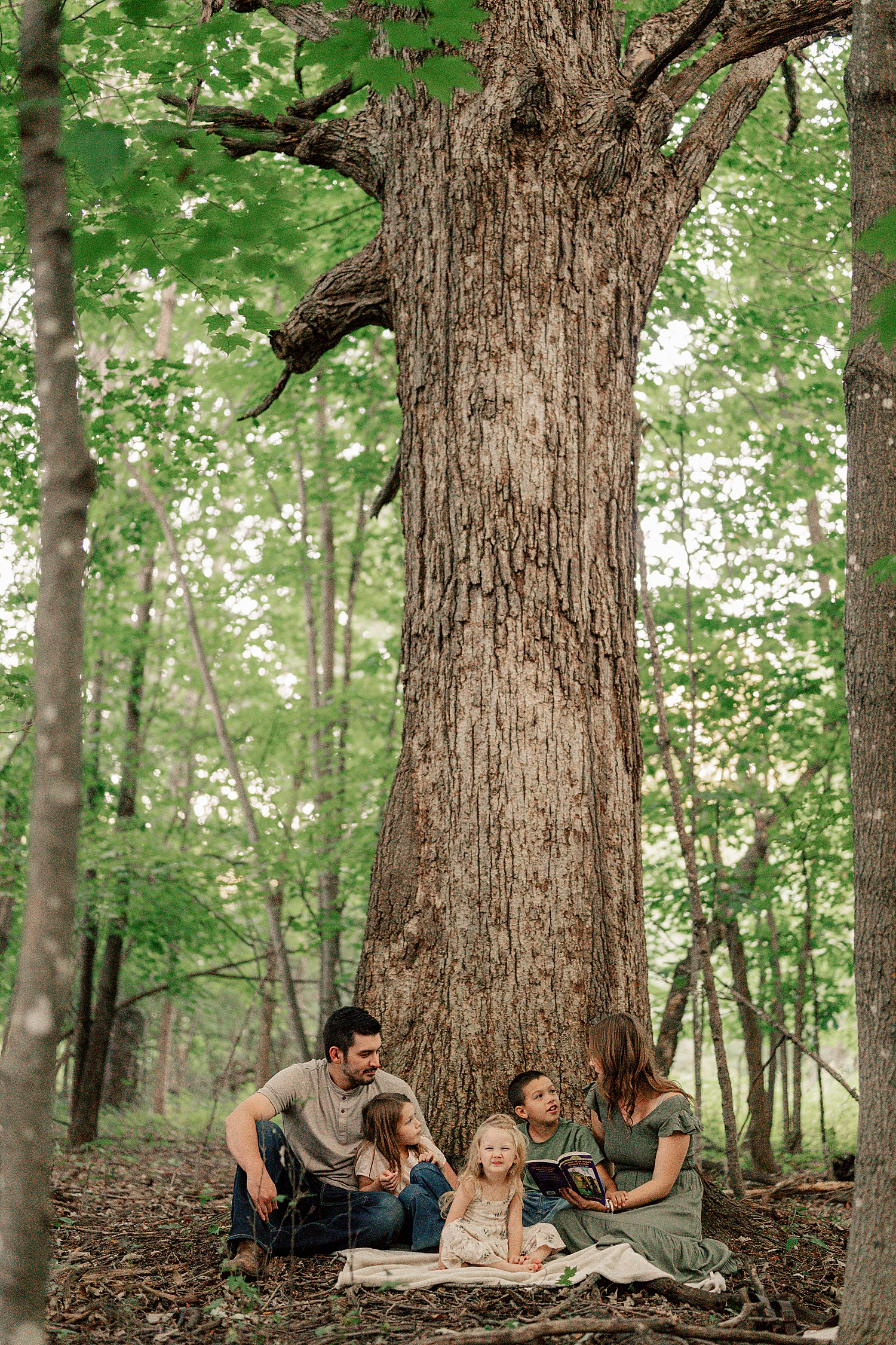 family of five nestled at the base of a tall tree by Rule Creative Co