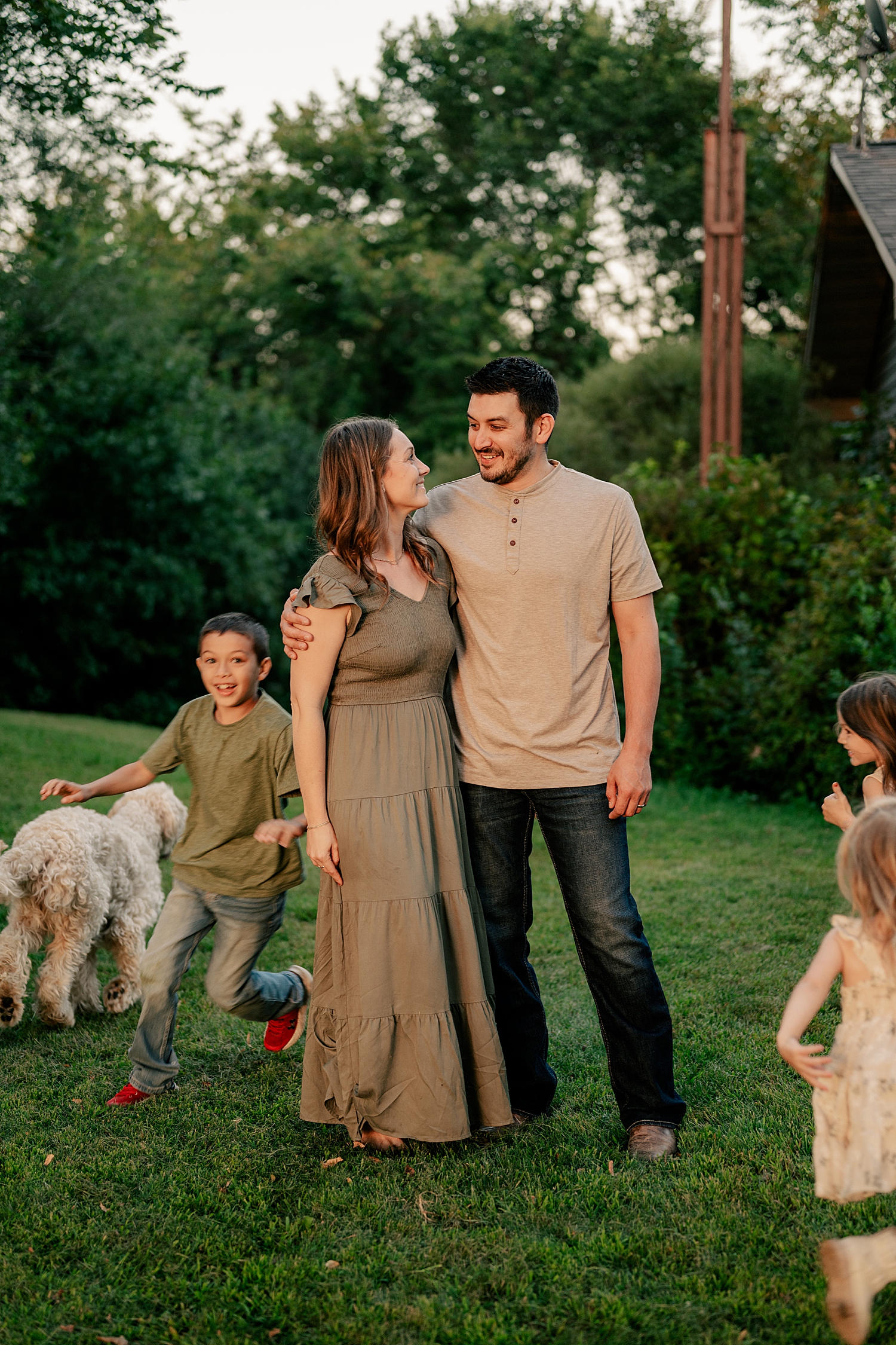 husband and wife look at each other while kids run around them by Rule Creative Co