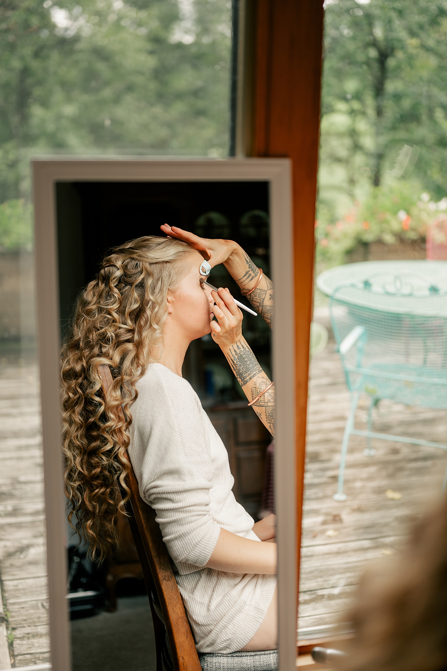 woman with long curly blonde hair getting her makeup done, by Minnesota wedding photographer