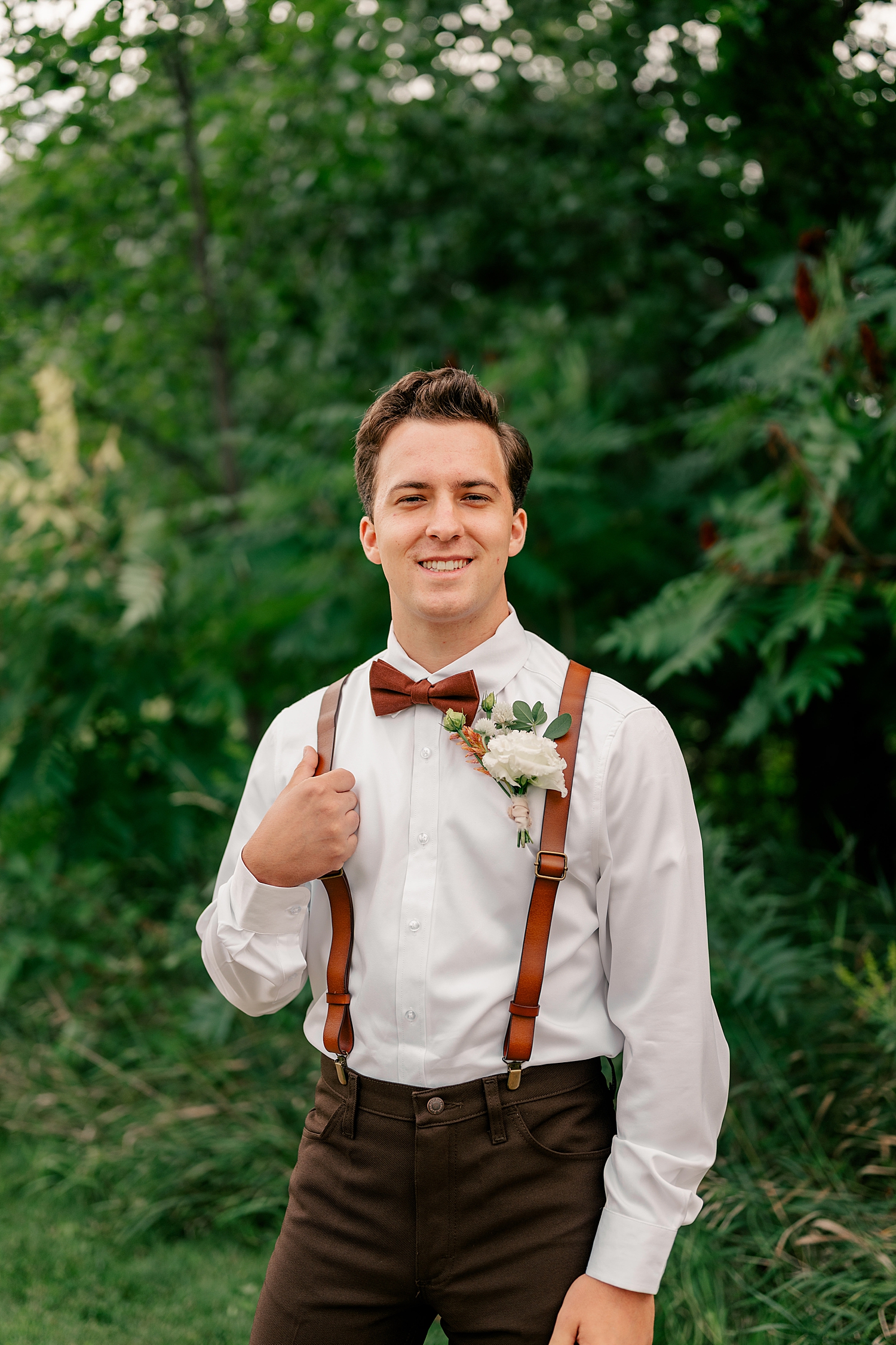 groom with brown bowtie and suspenders by Minnesota wedding photographer
