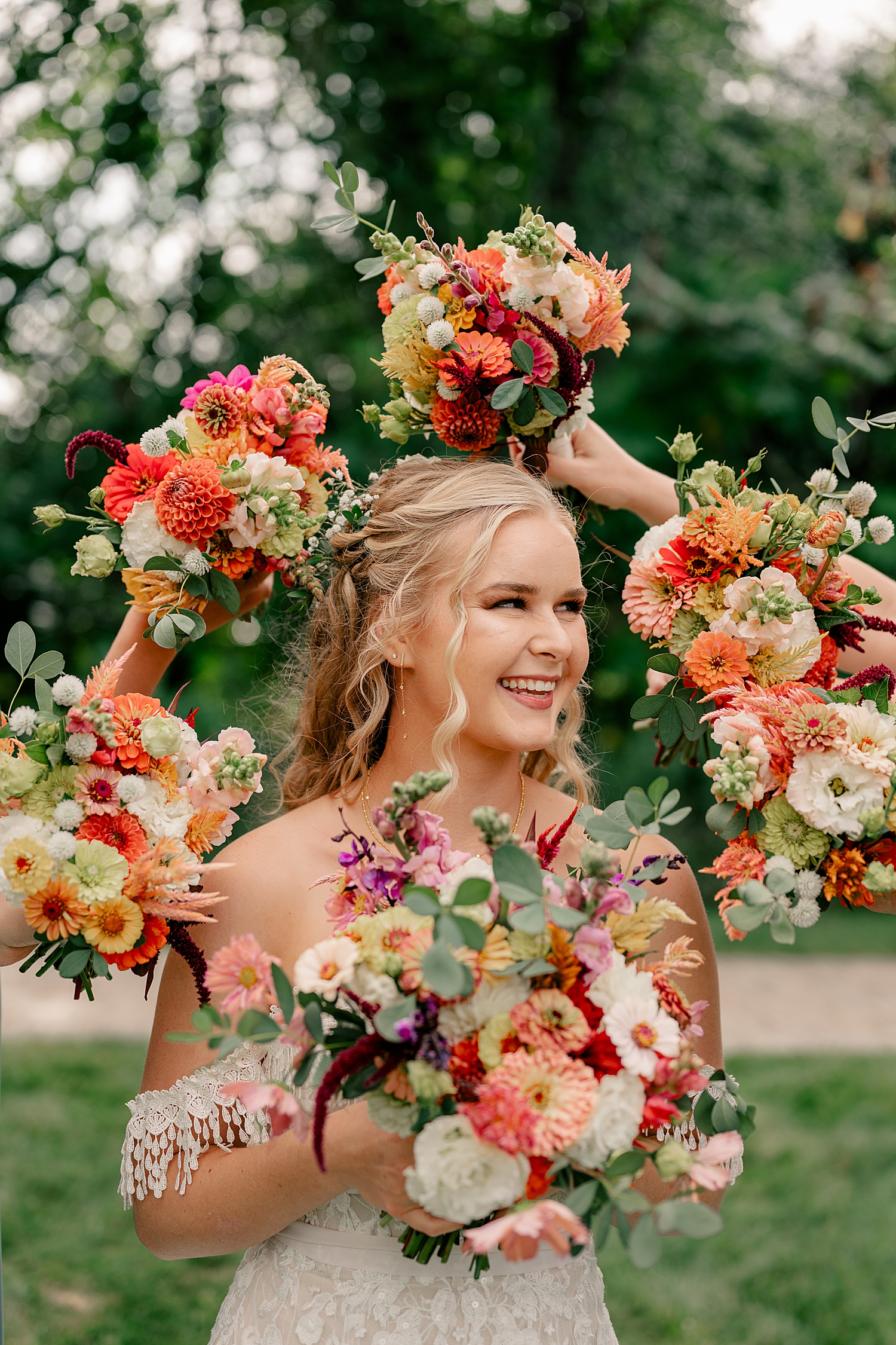 bridesmaids hold up colorful bouquest around their friend by Minnesota wedding photographer