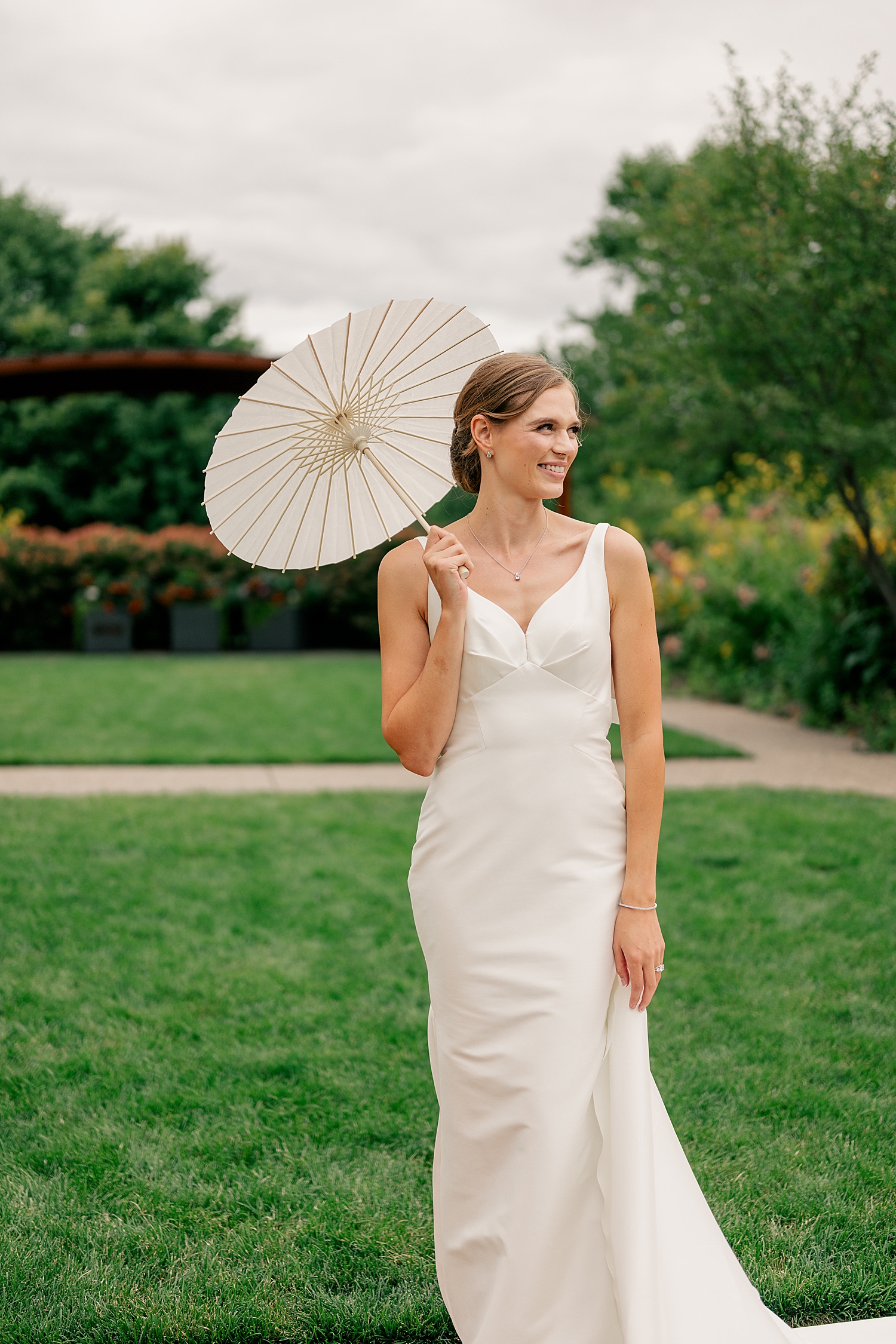 Minneapolis bride holds parasol on lawn by Minnesota photographer