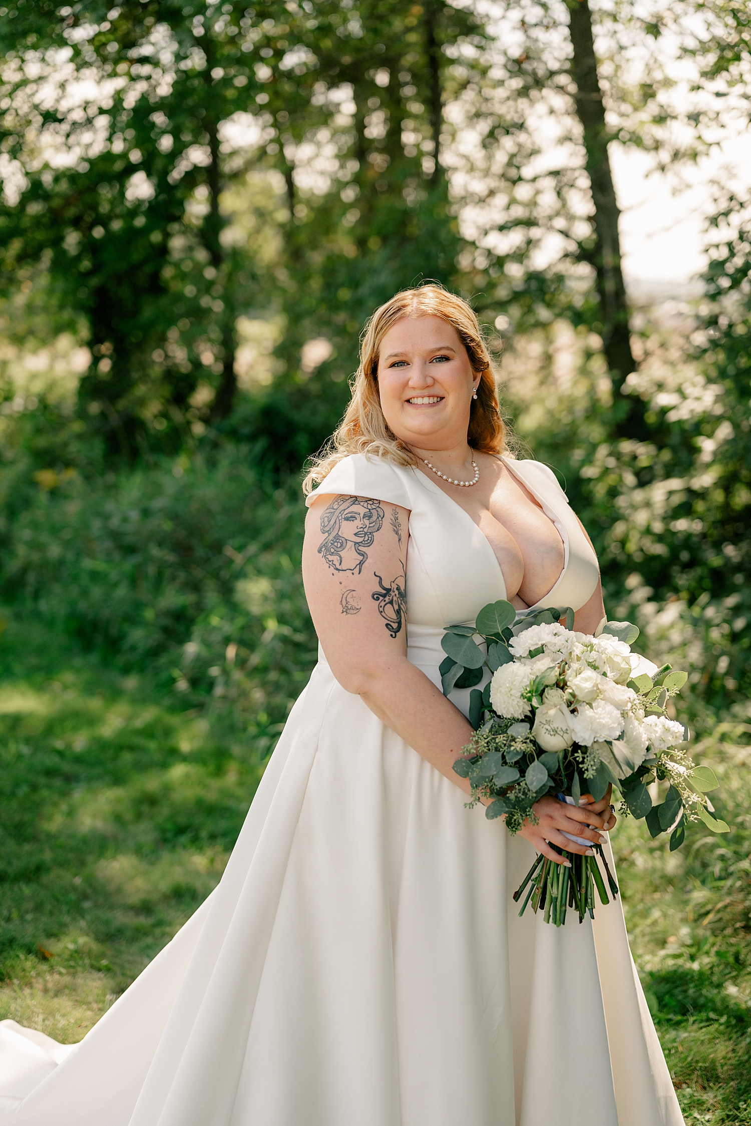 blonde bride in elegant silk gown stands on lawn by Minnesota elopement photographer