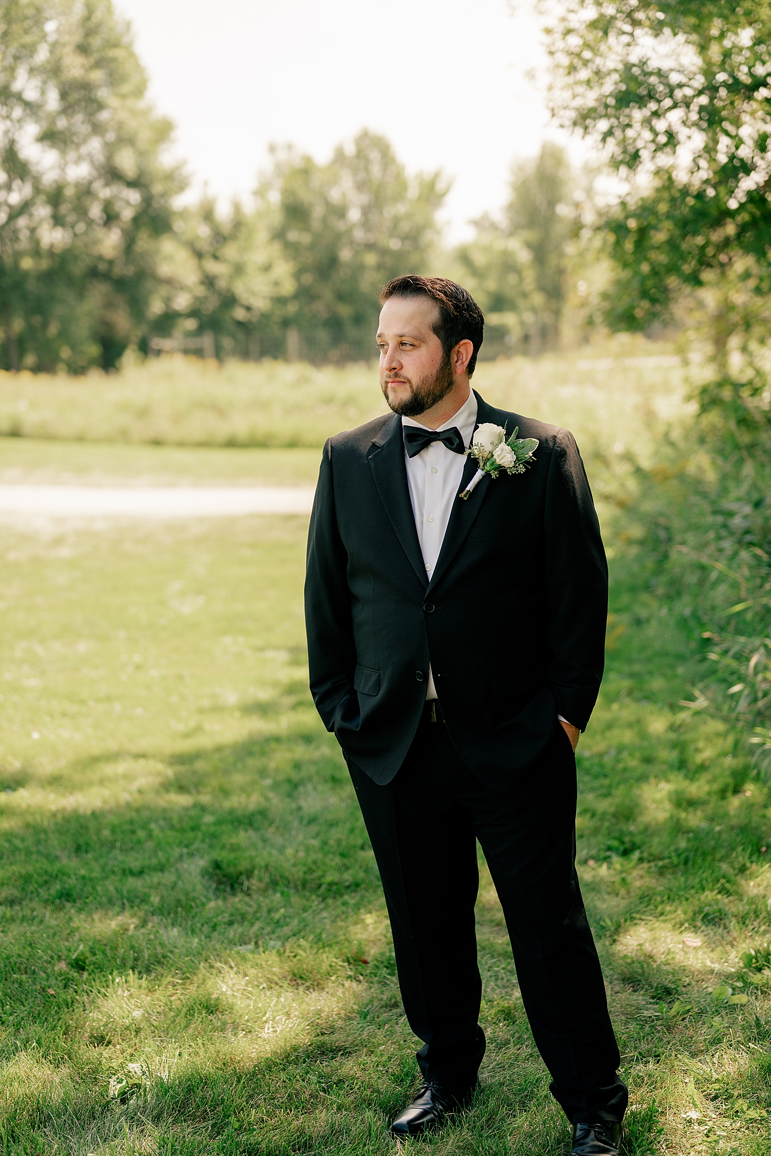 man in black tux stands in field in evening light by Rule Creative Co