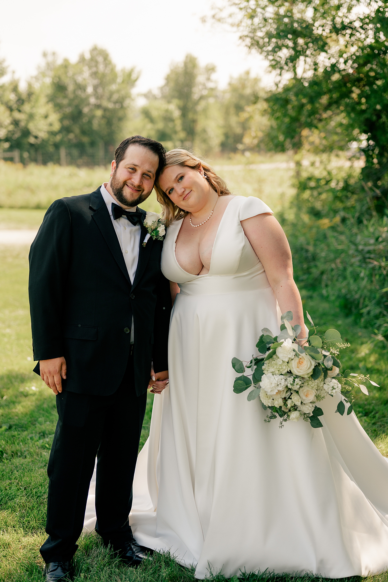 blonde bride in classic white dress leans on her man for August Minnesota Wedding