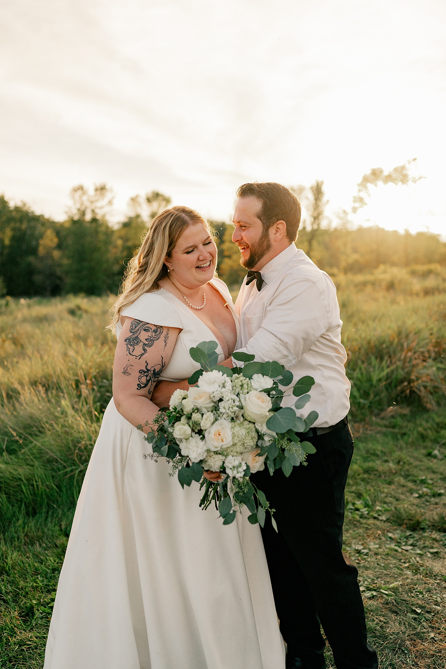 couple laugh together in golden hour, holding bouquet by Rule Creative Co