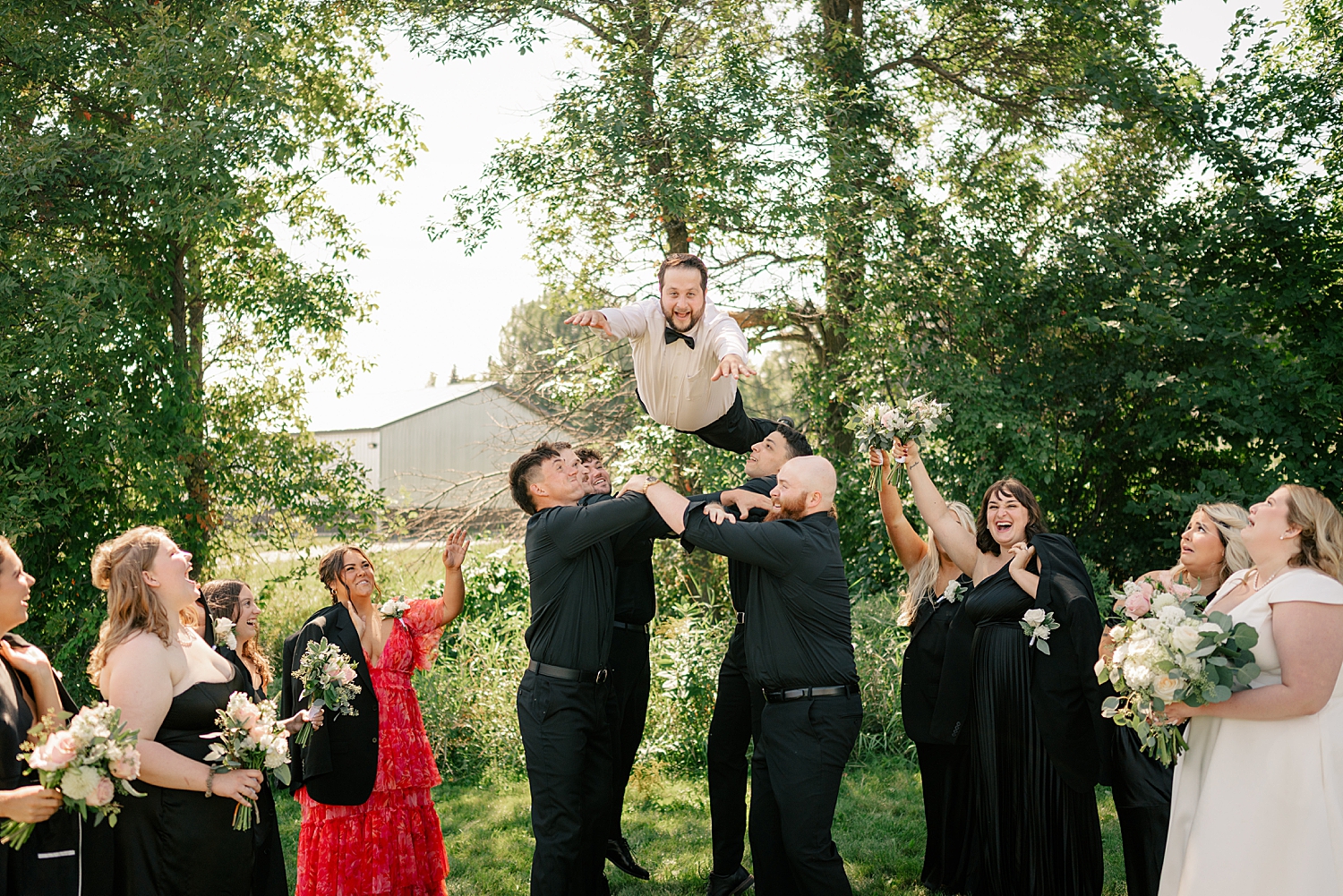 groomsmen toss groom in the air outside by Minnesota elopement photographer