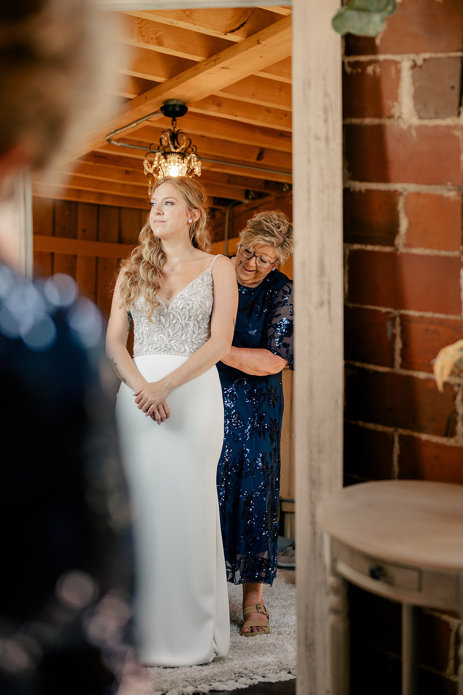 woman's grandma zips her into her bridal gown by Minnesota wedding photographer