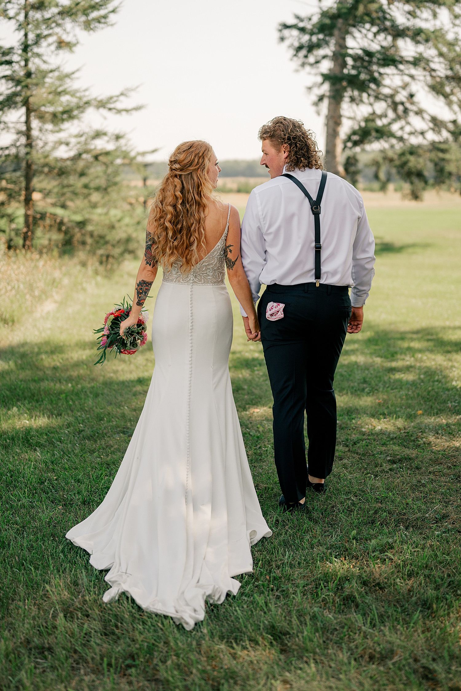 bride and groom walk through field by Rule Creative Co