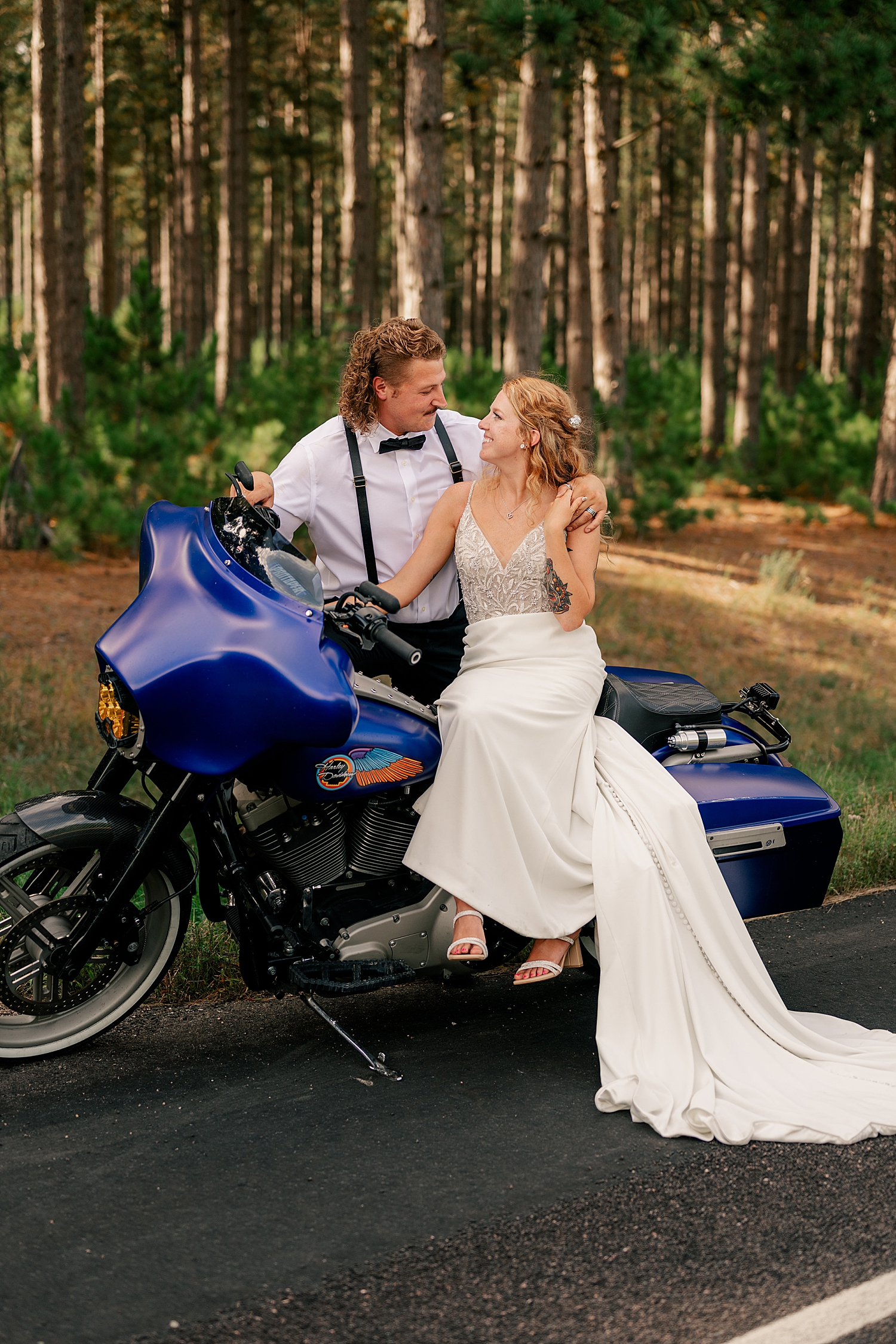 couple in bridal attire sit on blue motorcycle by Rule Creative Co