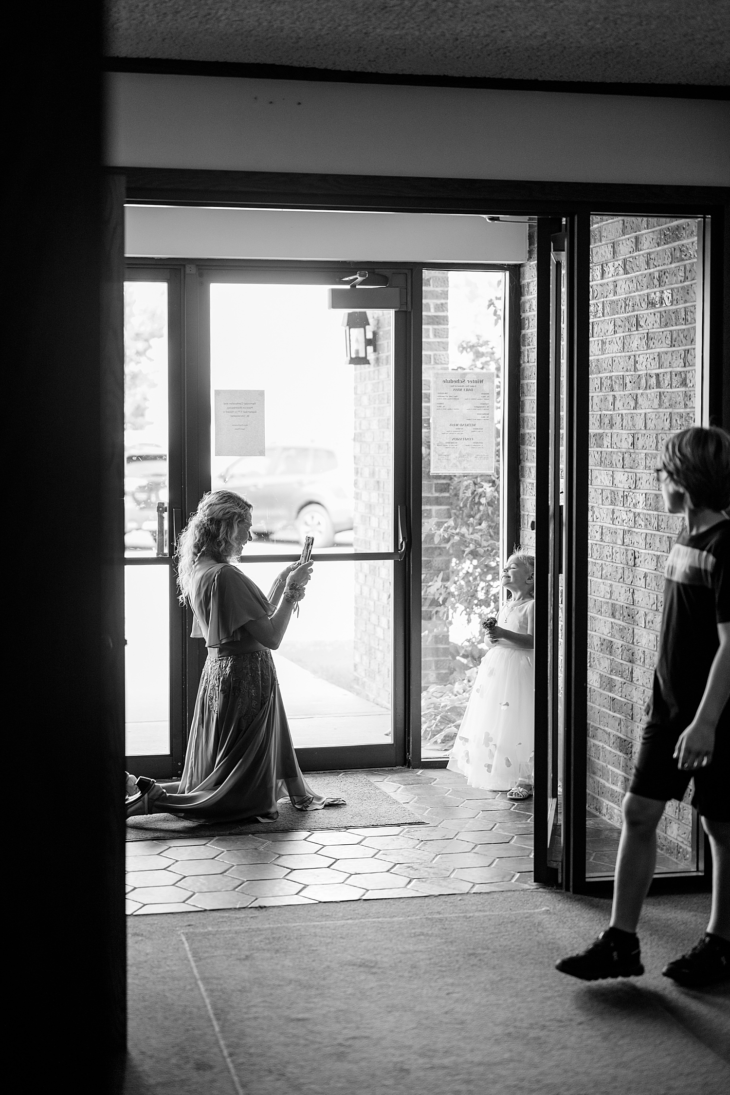 woman takes photo of flower girl before walking down the aisle at Red Oak Farm