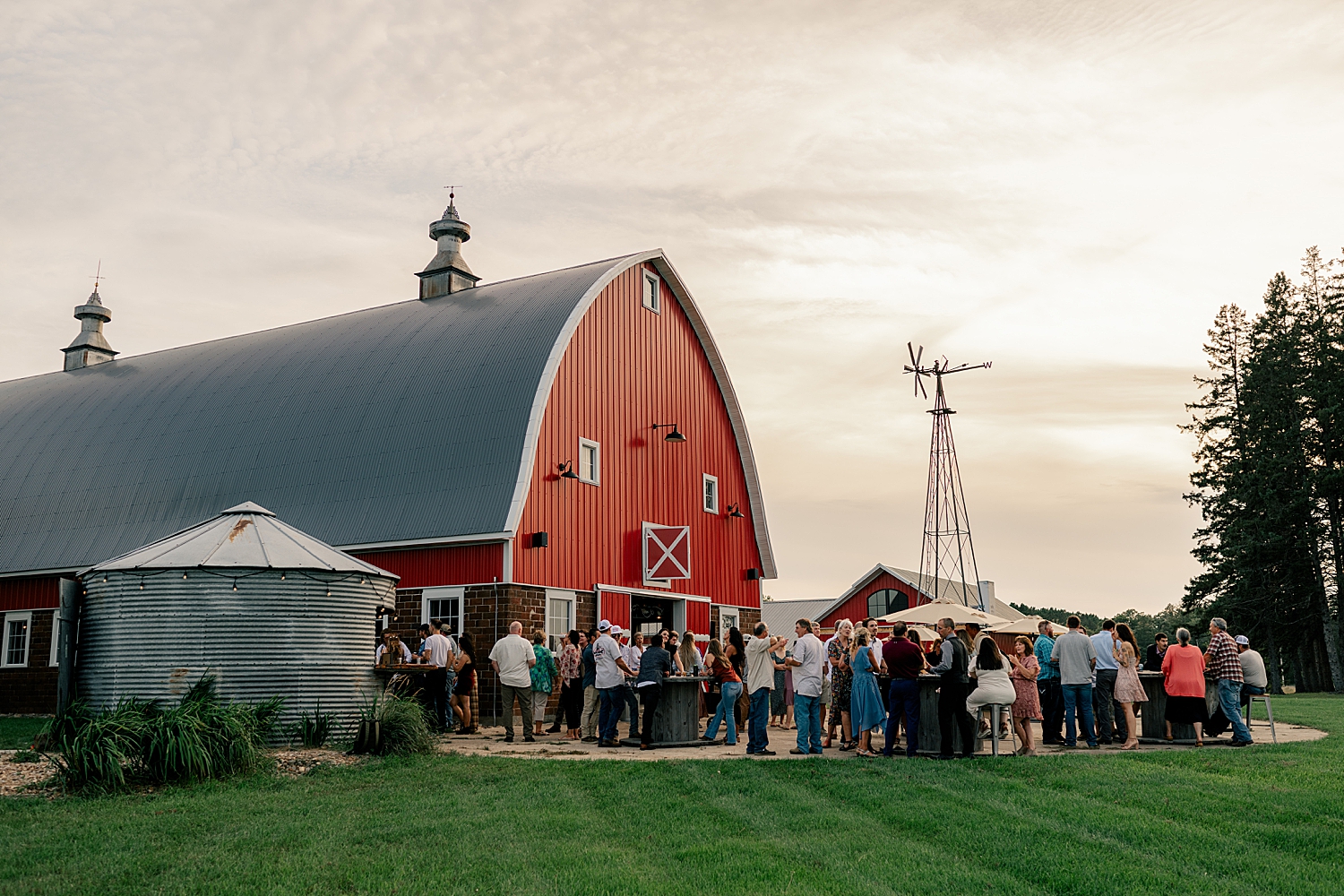 guests mingle outside big red structure by Minnesota wedding photographer