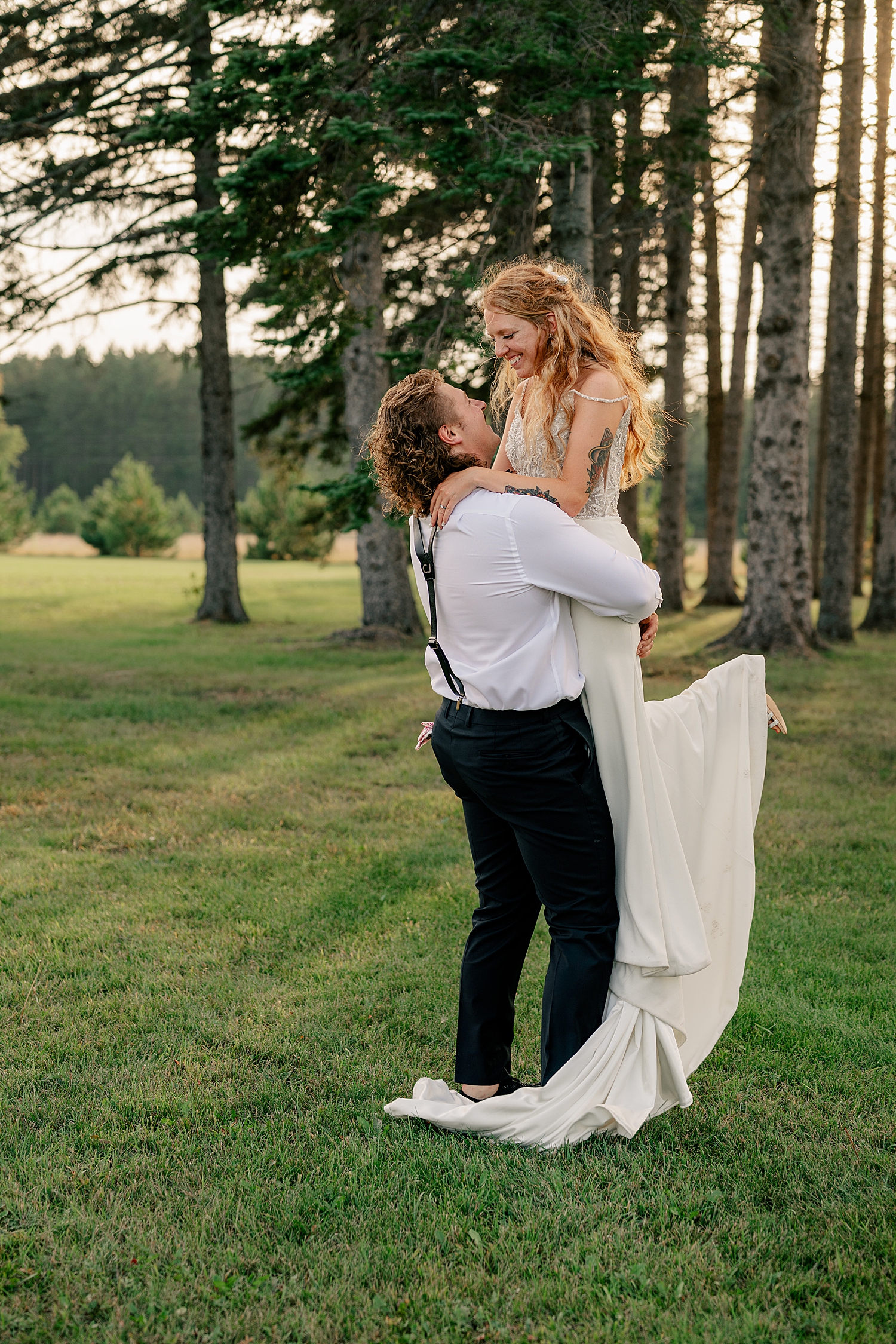 man lifts up his new wife in golden hour by Minnesota wedding photographer