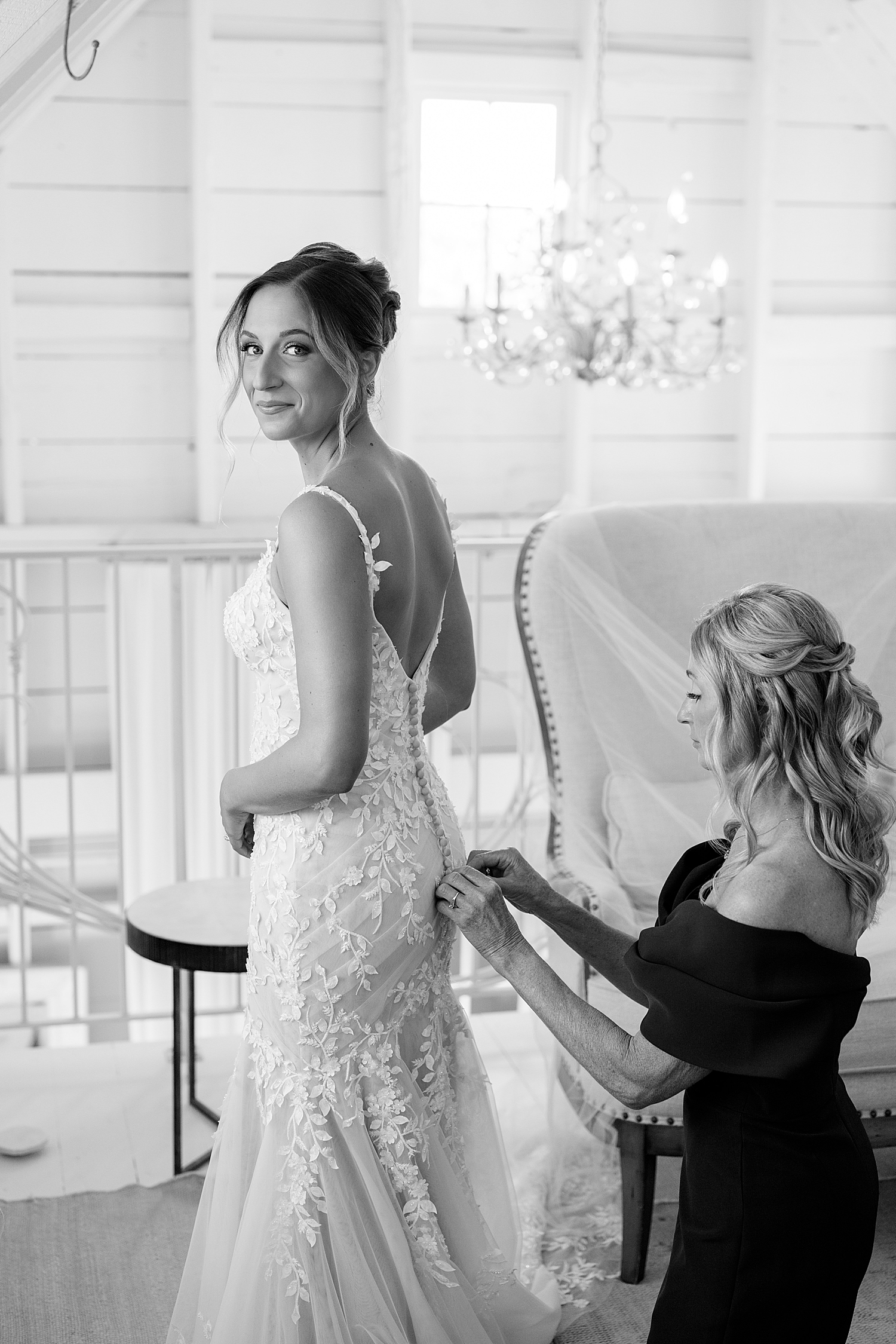 woman in bridal gown looks over her shoulder while bridesmaids fix buttons by Rule Creative Co