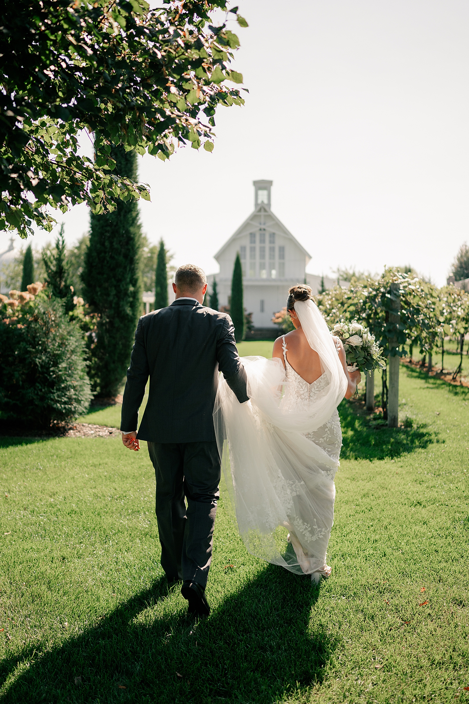 man and woman walk towards white barn by Minnesota wedding photographer