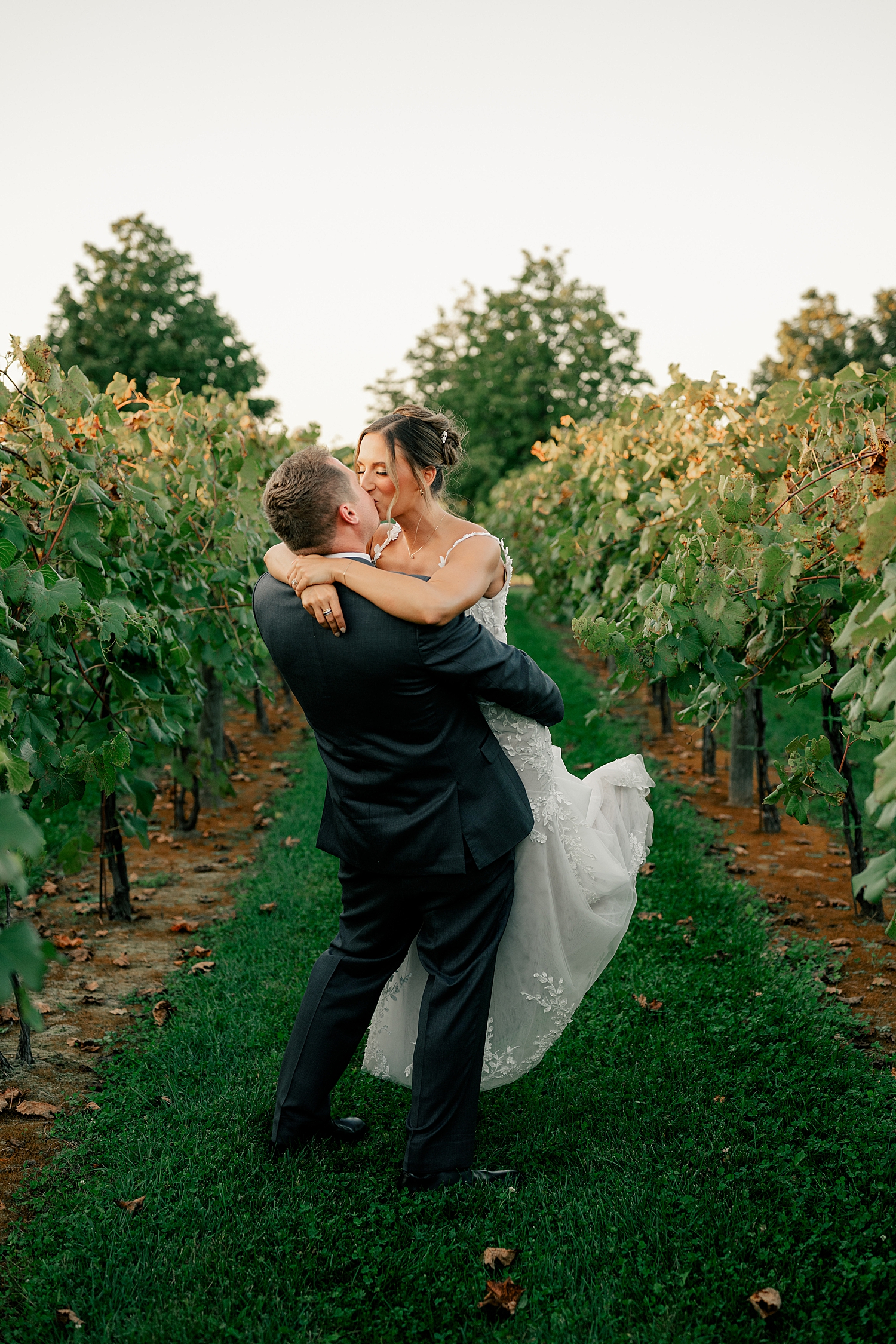 man lifts up bride to spin her around the vineyard by Minnesota wedding photographer