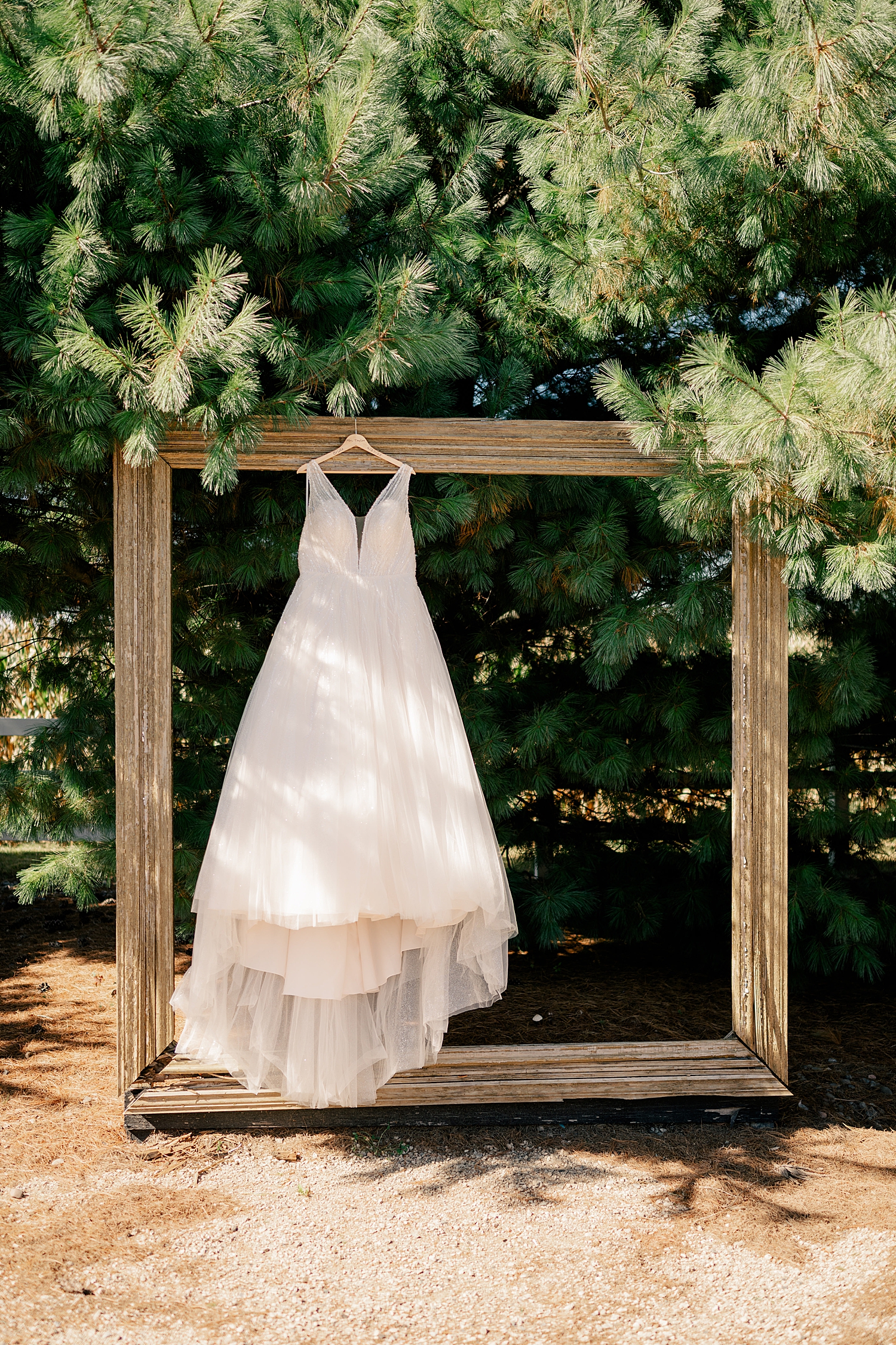 long white bridal gown hangs on wooden square by Rule Creative Co