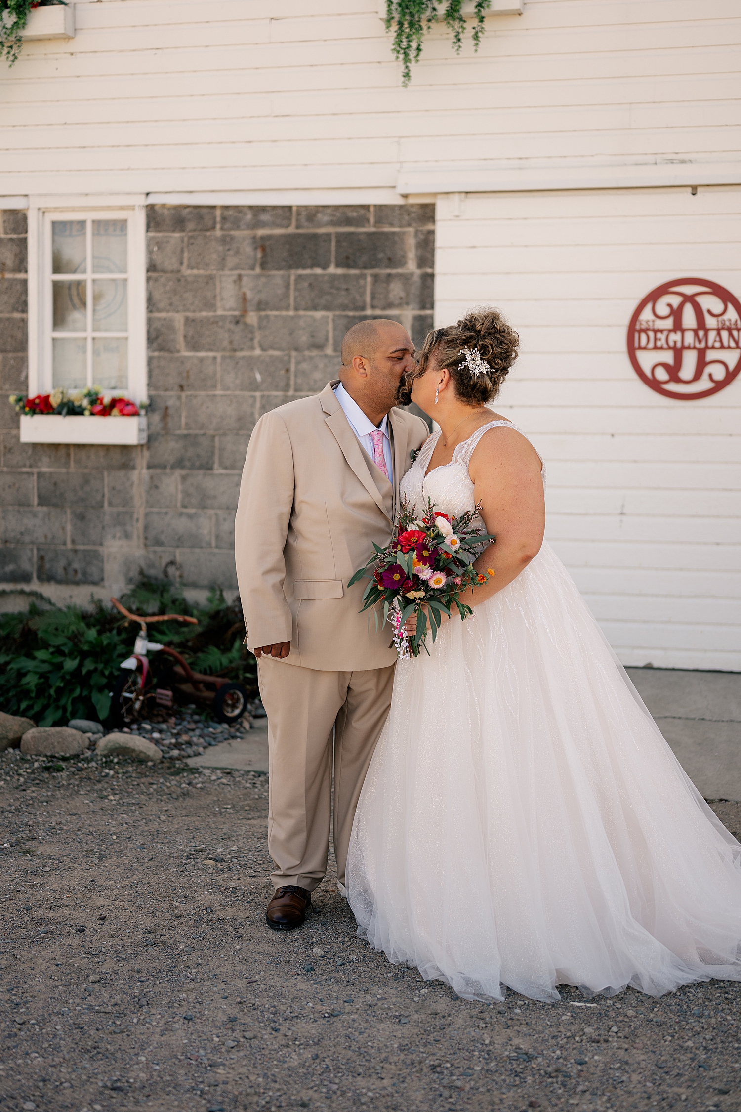 newlyweds share a kiss in front of white wall by Rule Creative Co