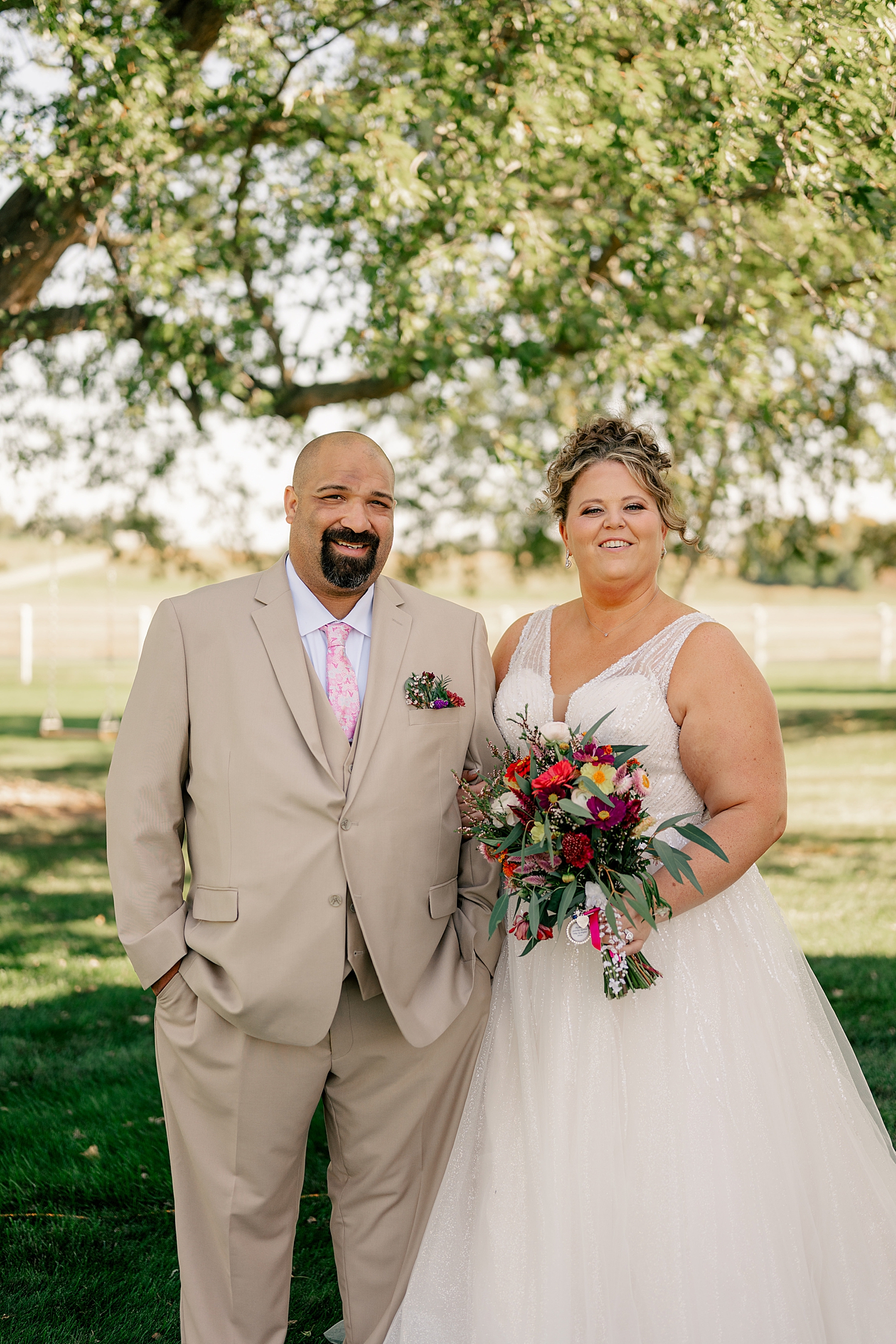 newlyweds under a big tree on lawn at Historic Deglman Farm