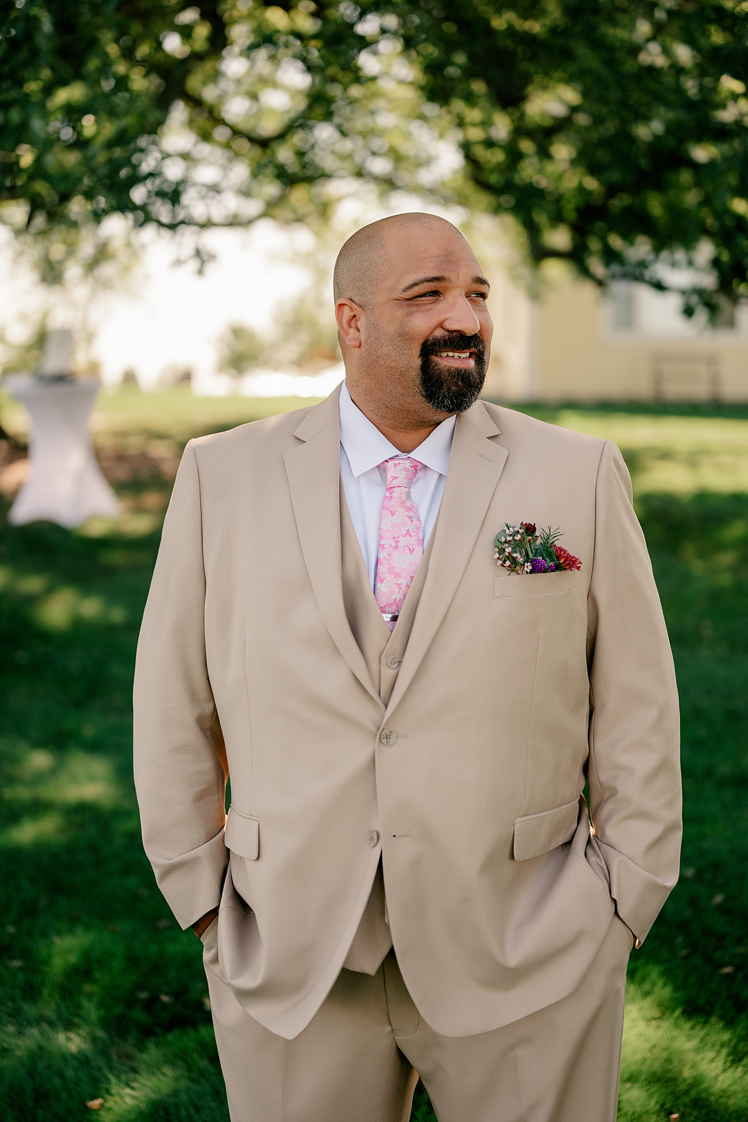groom in tan suit looks out over lawn by Rule Creative Co