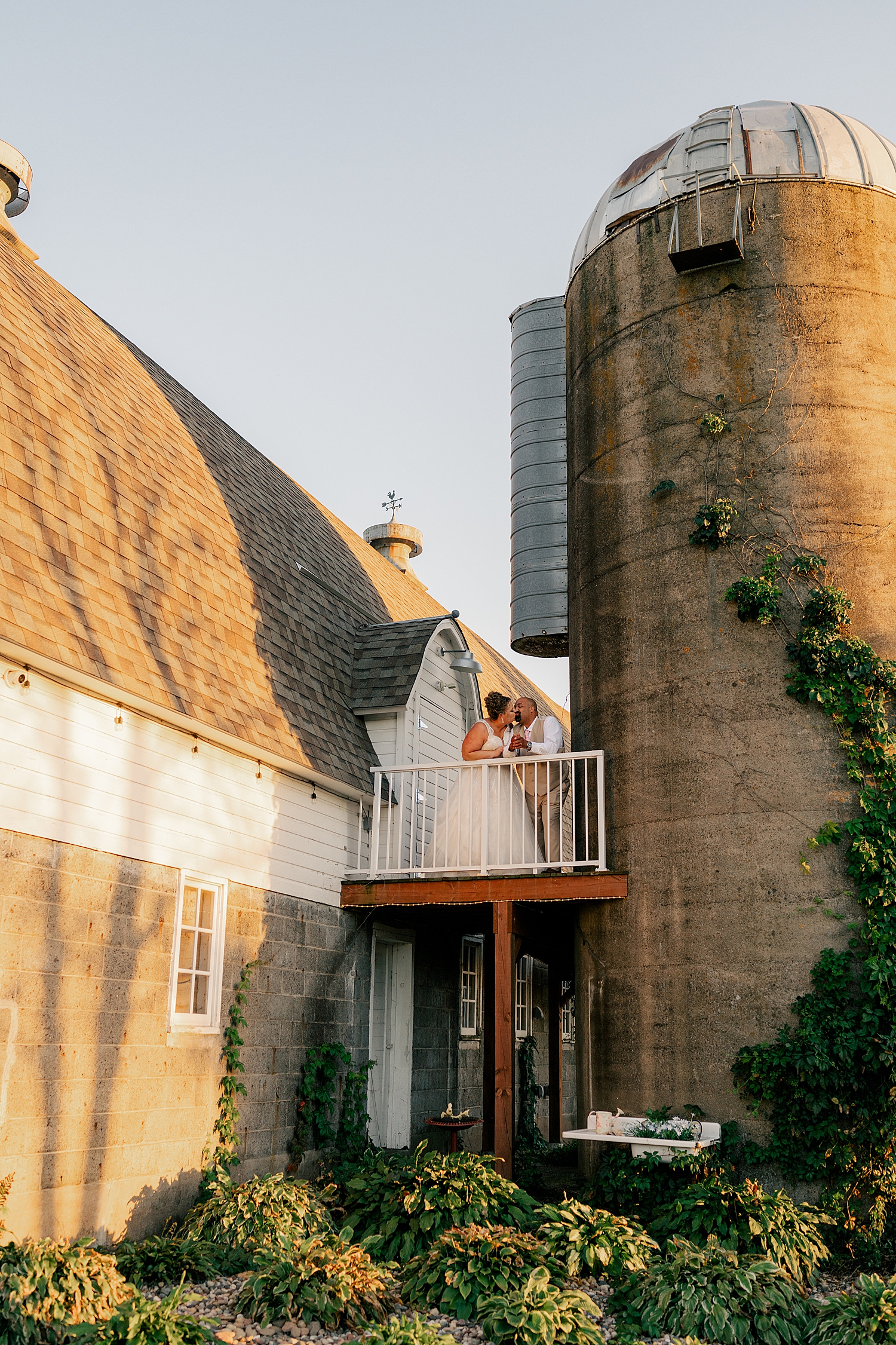 man and woman stand on balcony by silos by Minnesota wedding photographer