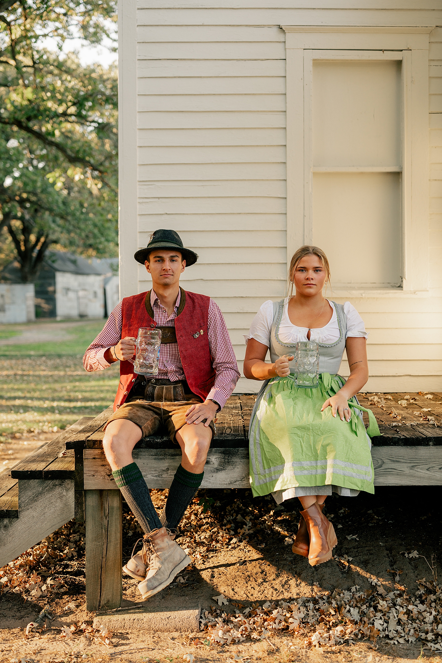 couple in liederhosen and dirndel sit on porch by Minnesota wedding photographer