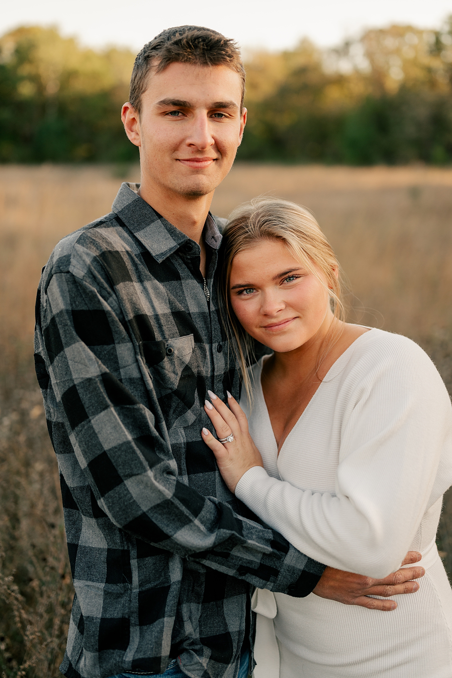 blonde woman leans into her man in a field by Minnesota wedding photographer
