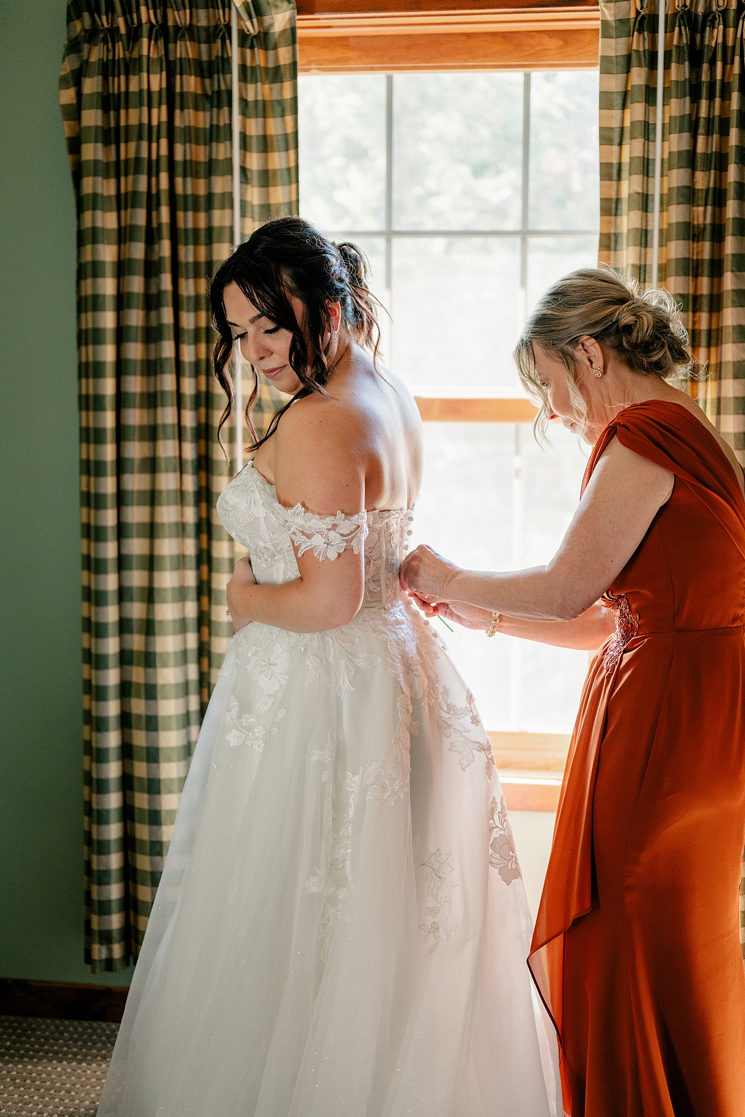 woman in long white dress gets zipped in by mother by Rule Creative Co