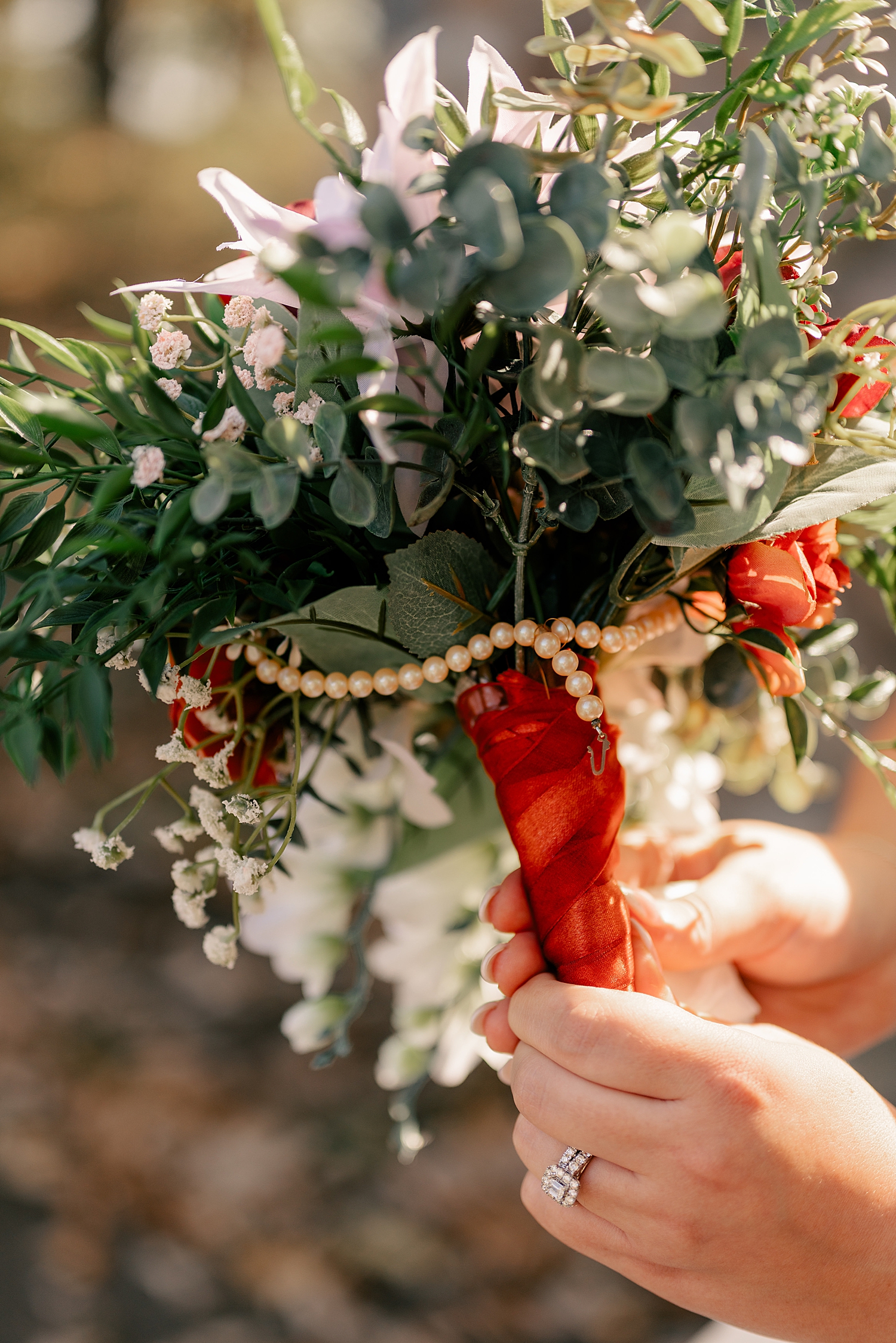 bride shows off her flowers with antique pearls at Breezy Point venue