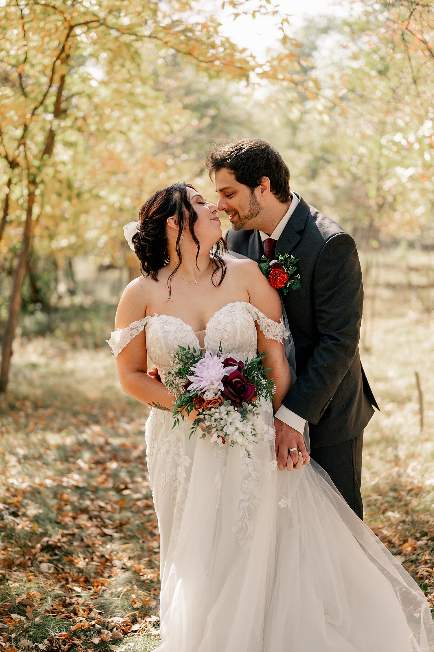 bride and groom snuggle a kiss under trees by Minnesota wedding photographer