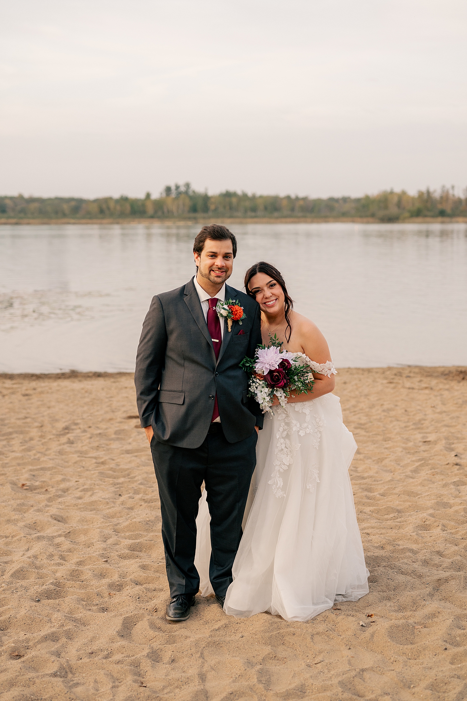 newlyweds stand on the beach and smile at Breezy Point venue