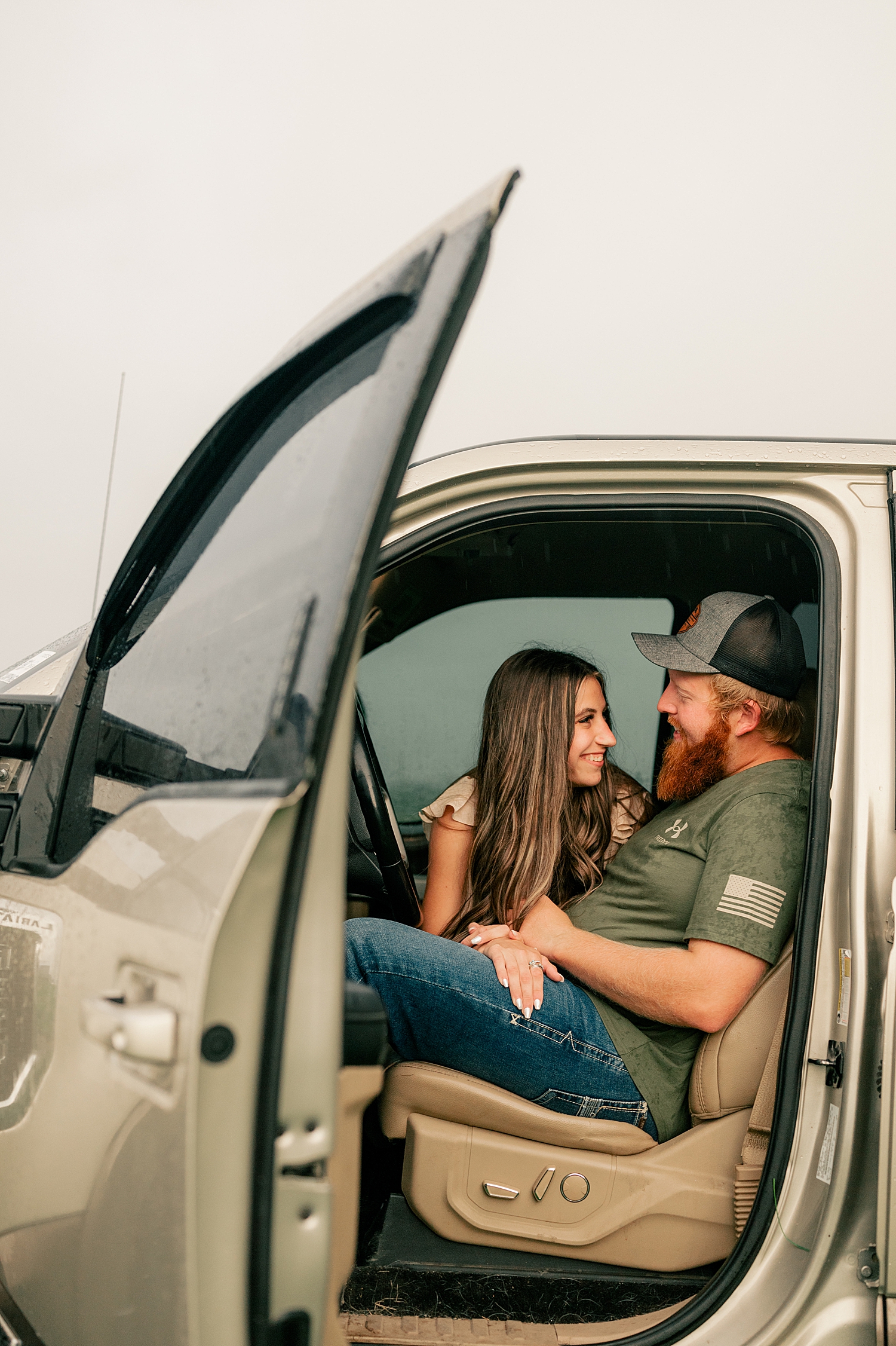 man and woman snuggle close in pickup truck by Minnesota wedding photographer