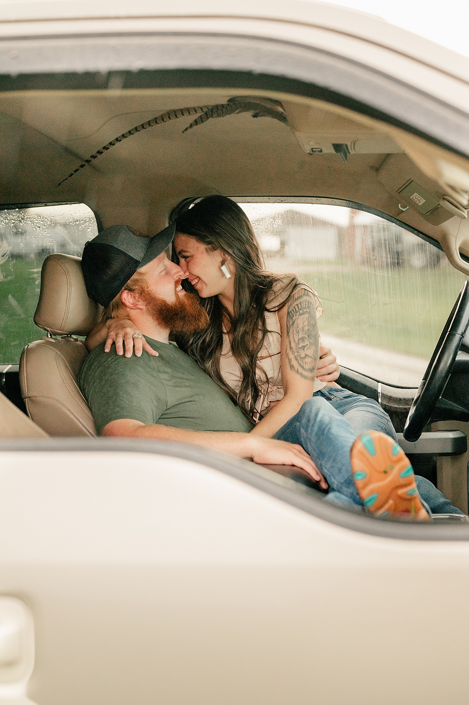 brunette bride to be sits on man's lap in car by Minnesota wedding photographer
