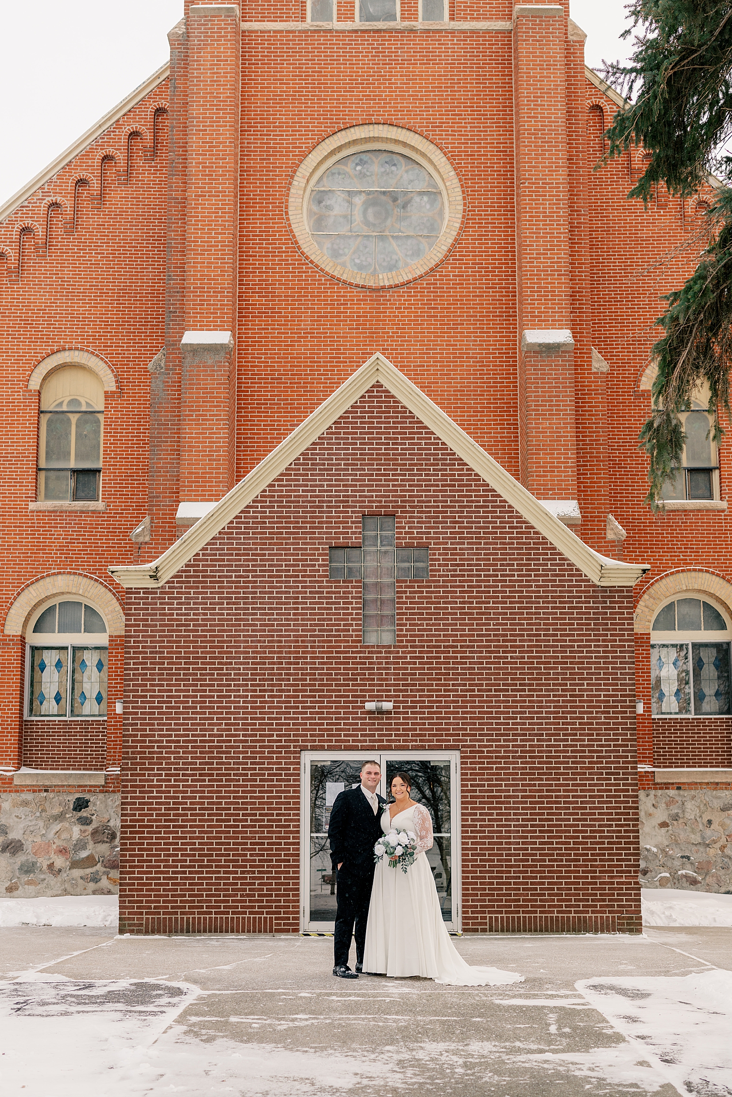 bride and groom stand outside door to church by Midwest photographer