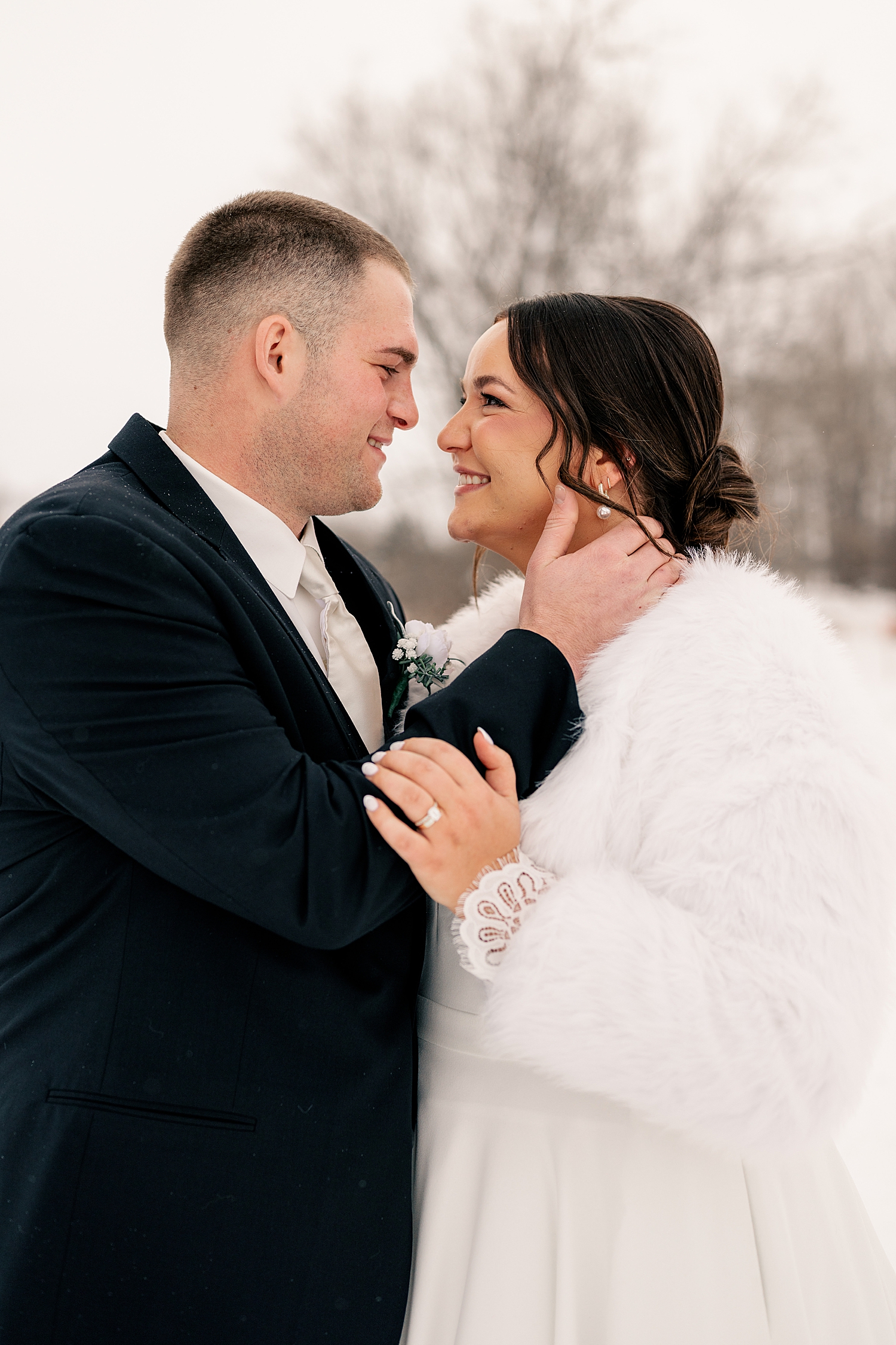 newlyweds hold each other close in the cold for Snowy December Minnesota wedding