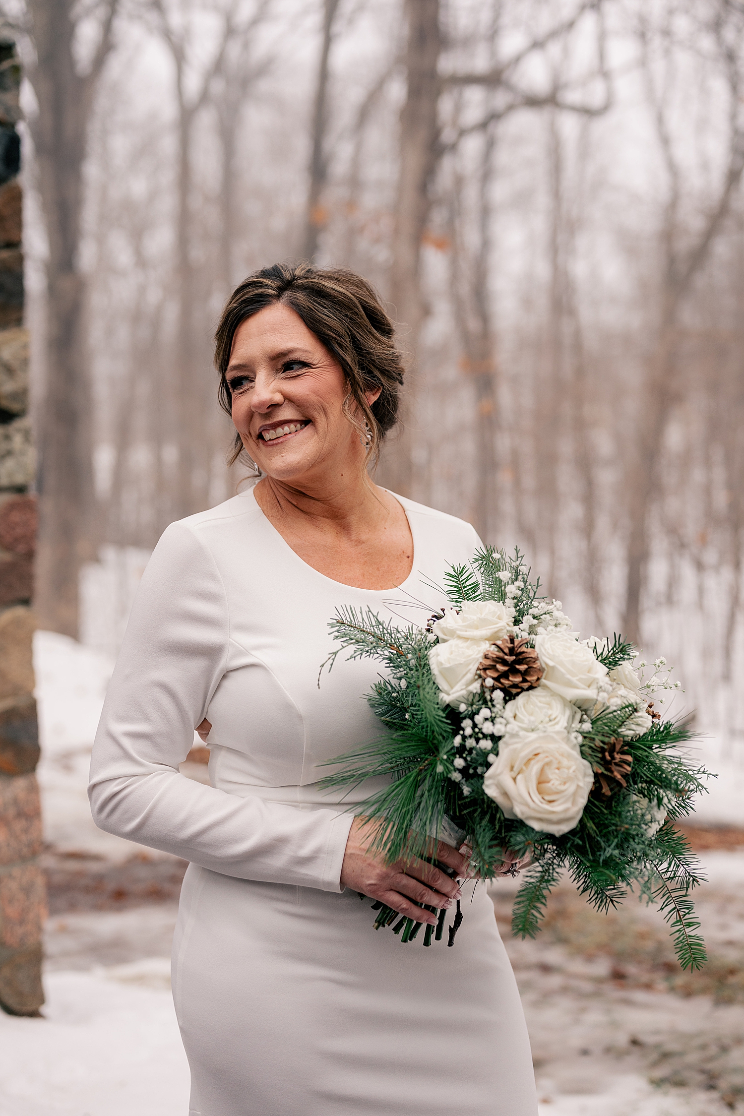 brunette mature bride carries bouquet in the snow by Minnesota wedding photographer