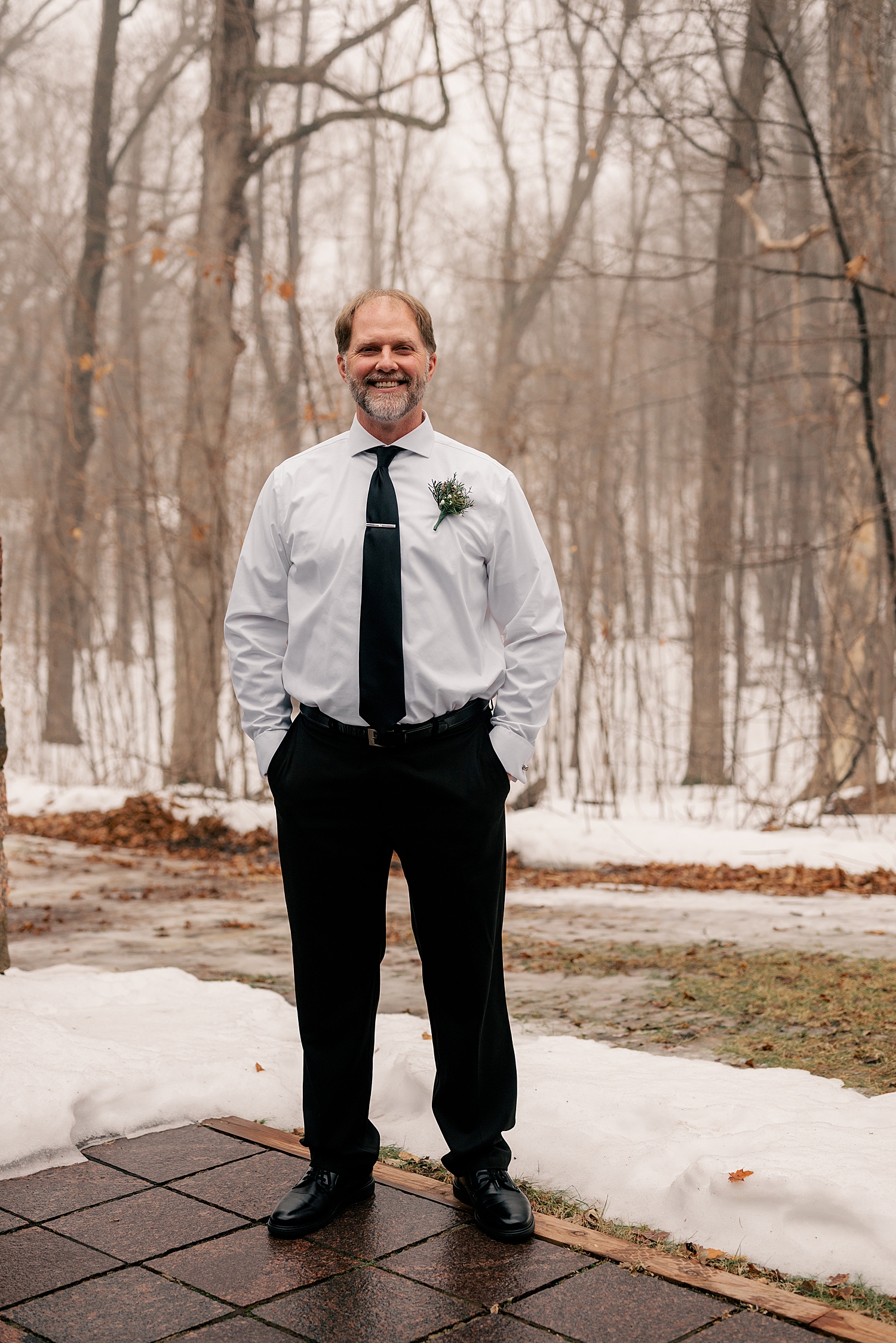 groom stands on patio surrounded by snow by Rule Creative Co