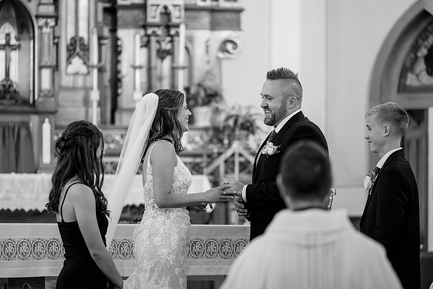 groom smiles at the altar exchanging rings with wife by Minnesota wedding photographer